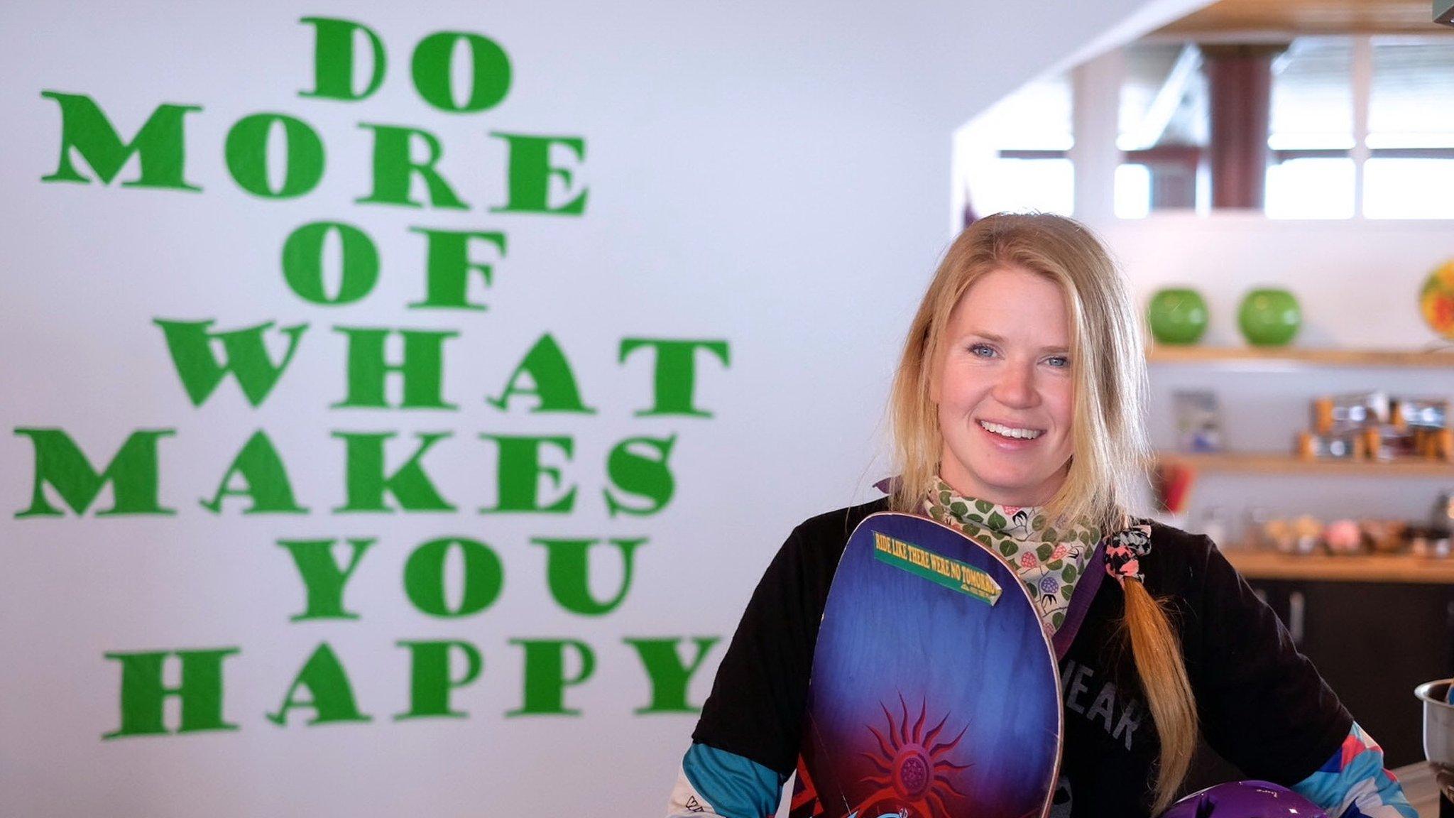 Charlie standing in front of a sign saying "Do more of what makes you happy"