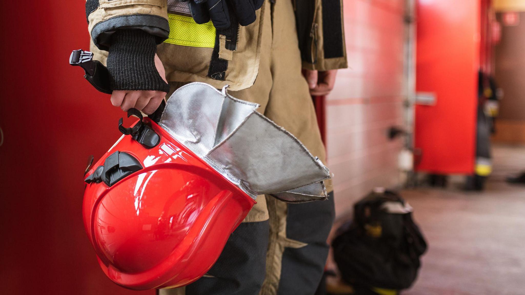 A stock image of a red helmet in fireman's hand