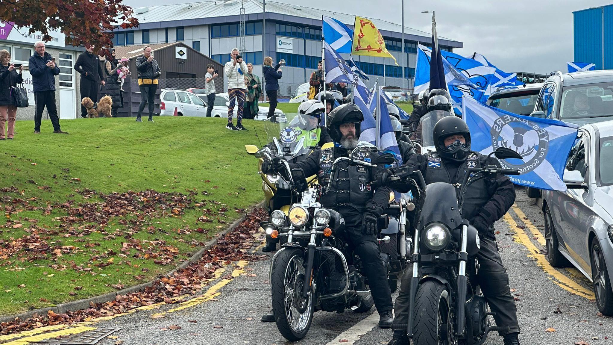 People on motorbikes which flags attached to them gather at Aberdeen airport