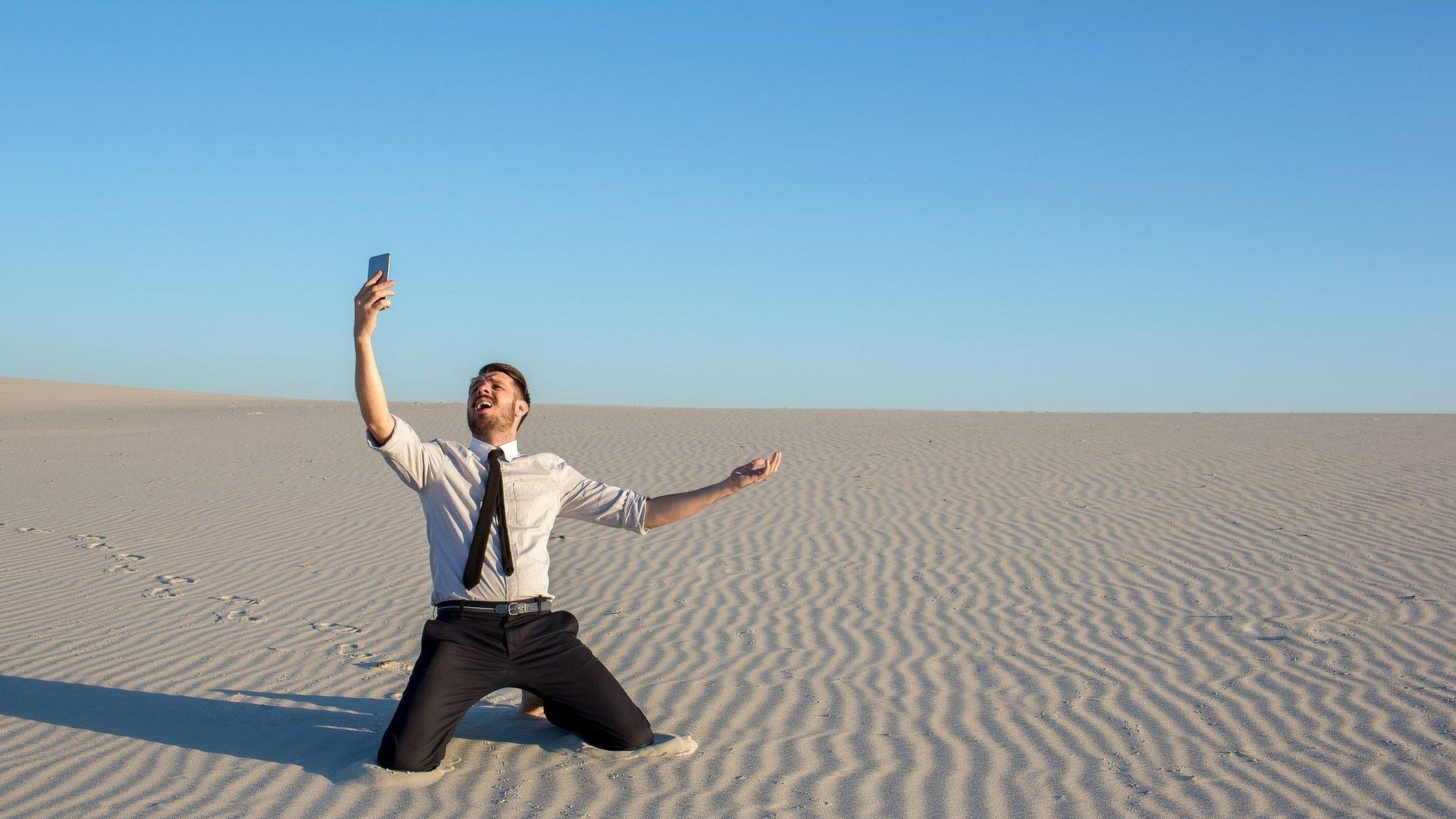 Man in desert searching for mobile phone signal