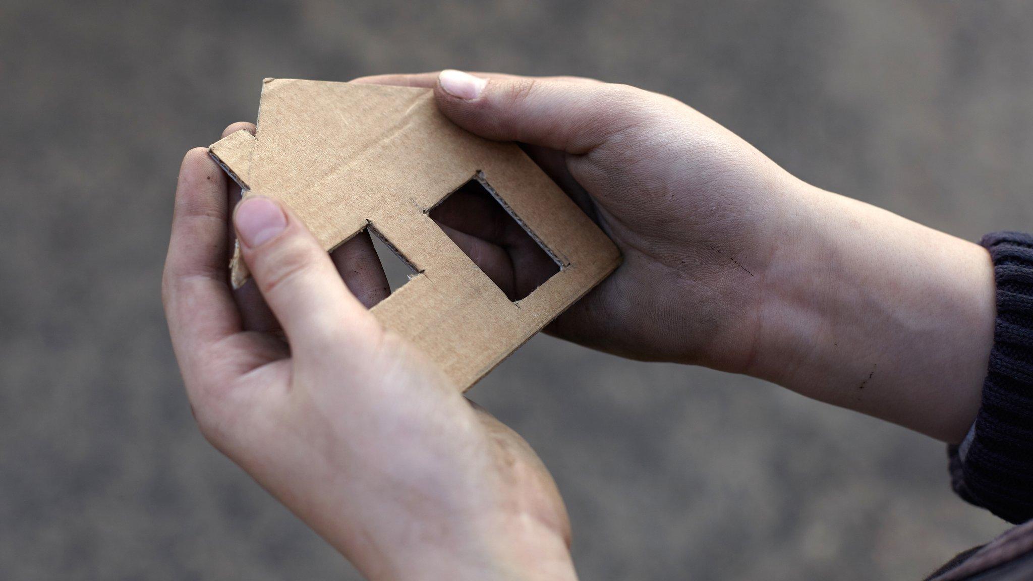 man holds cardboard house