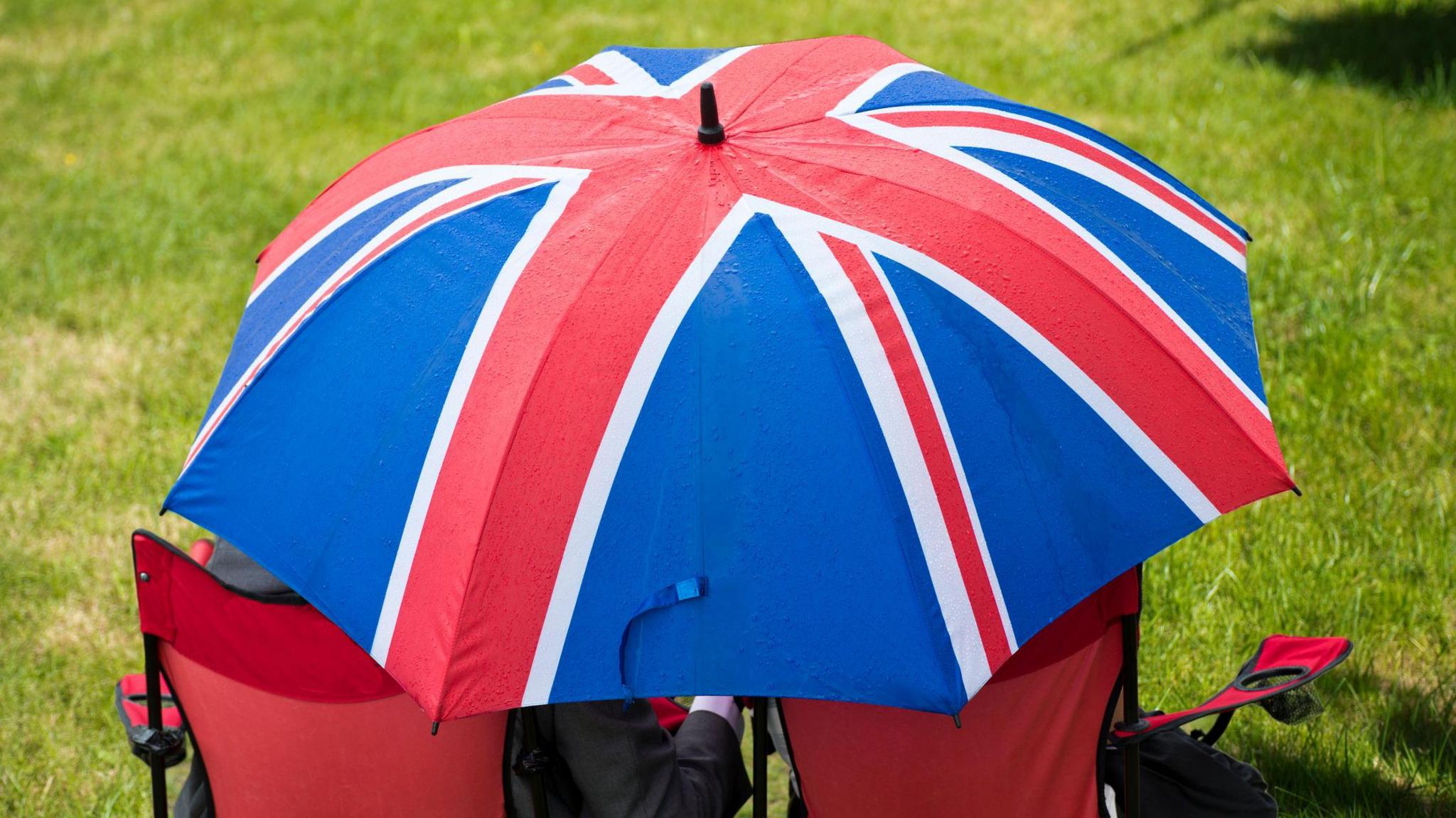 People huddle under an umbrella