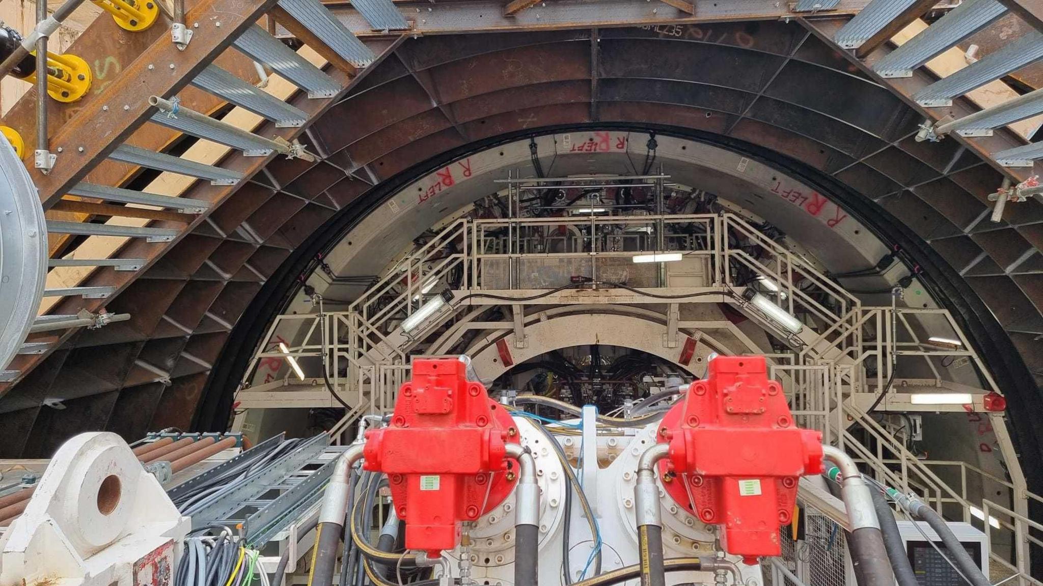 Image from 2022 showing the red and white metal machinery of the the tunnel boring machine at Royal Docks