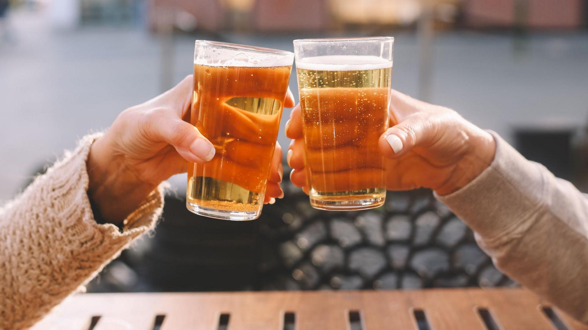 A stock image of two pints of beer being clinked together.