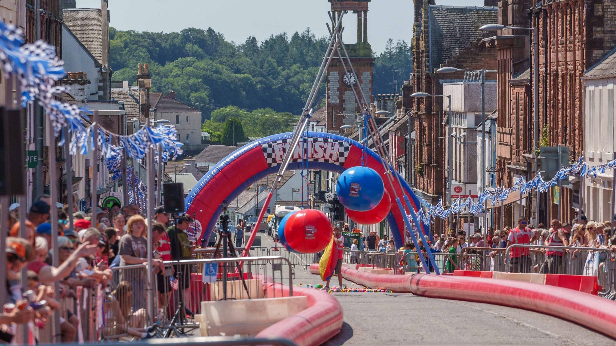 A winding track looking down the street towards a large red and blue blow-up finsih line.