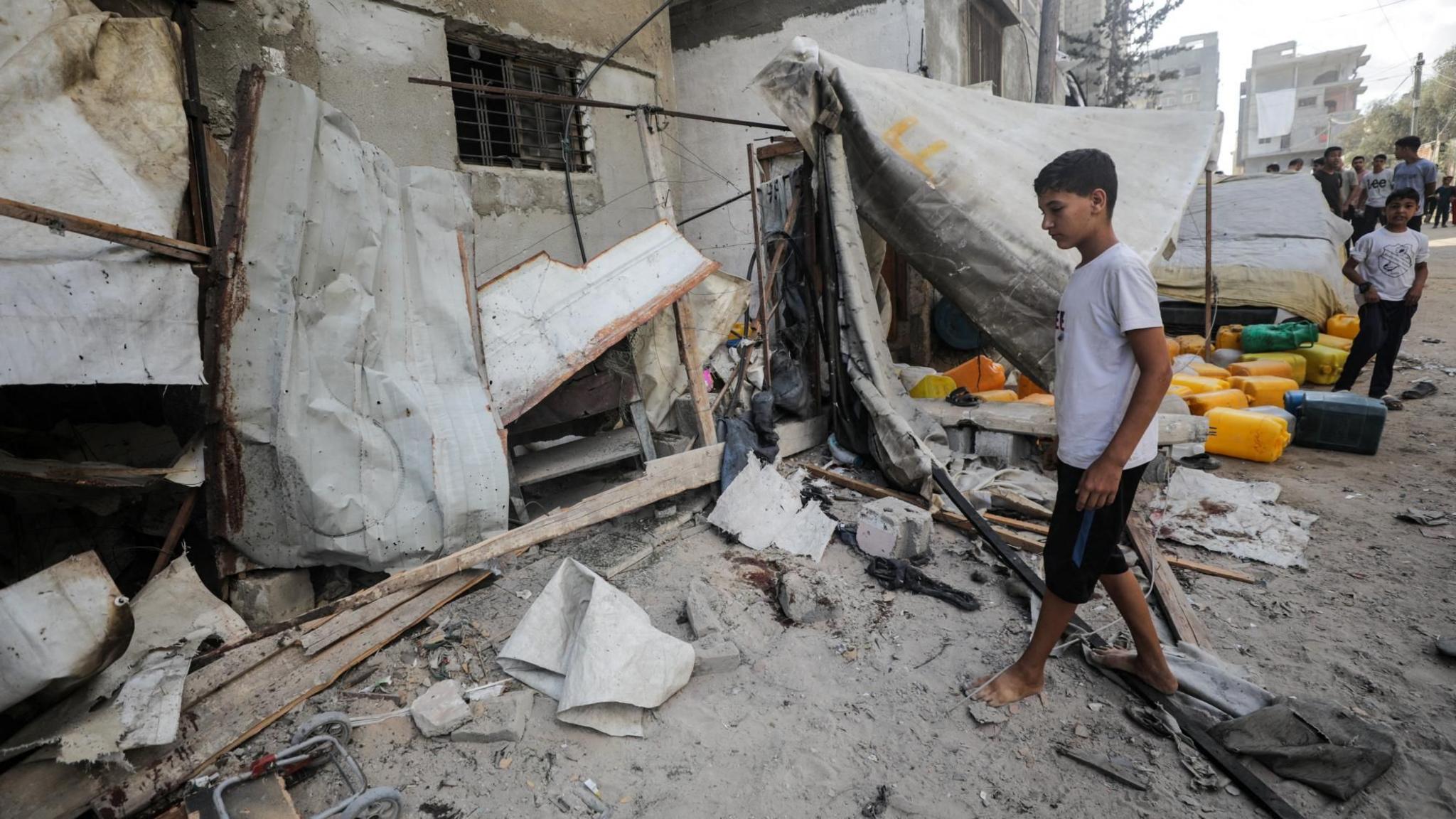 A Palestinian boy inspects the site of an Israeli strike that killed 10 Palestinians, including six children, who were queueing at a water distribution point, in Nuseirat refugee camp, central Gaza (13 July 2025)