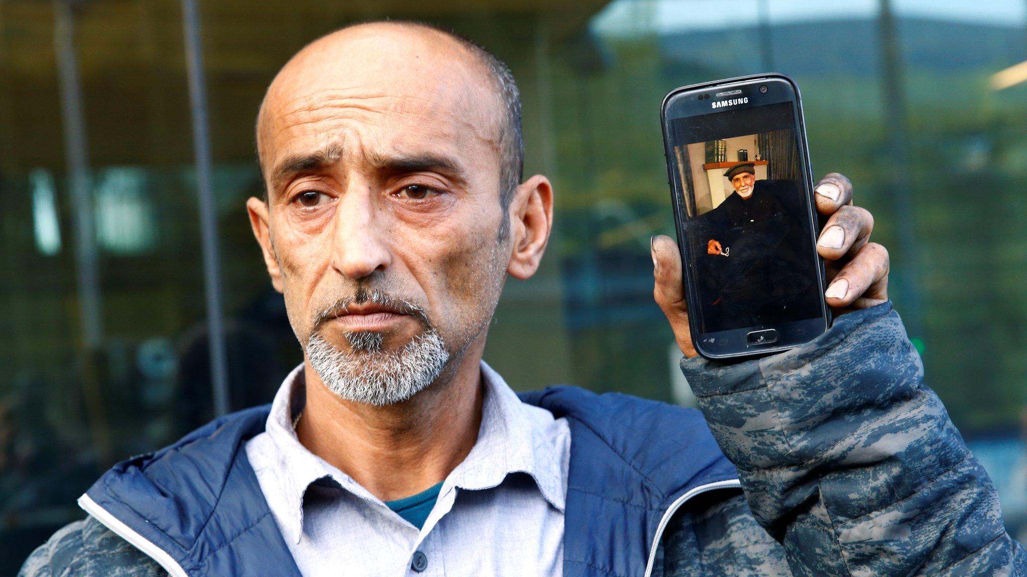 Omar Nabi holds a phone with a picture of his father Daoud, who died in the Christchurch mosque shootings (16 March)