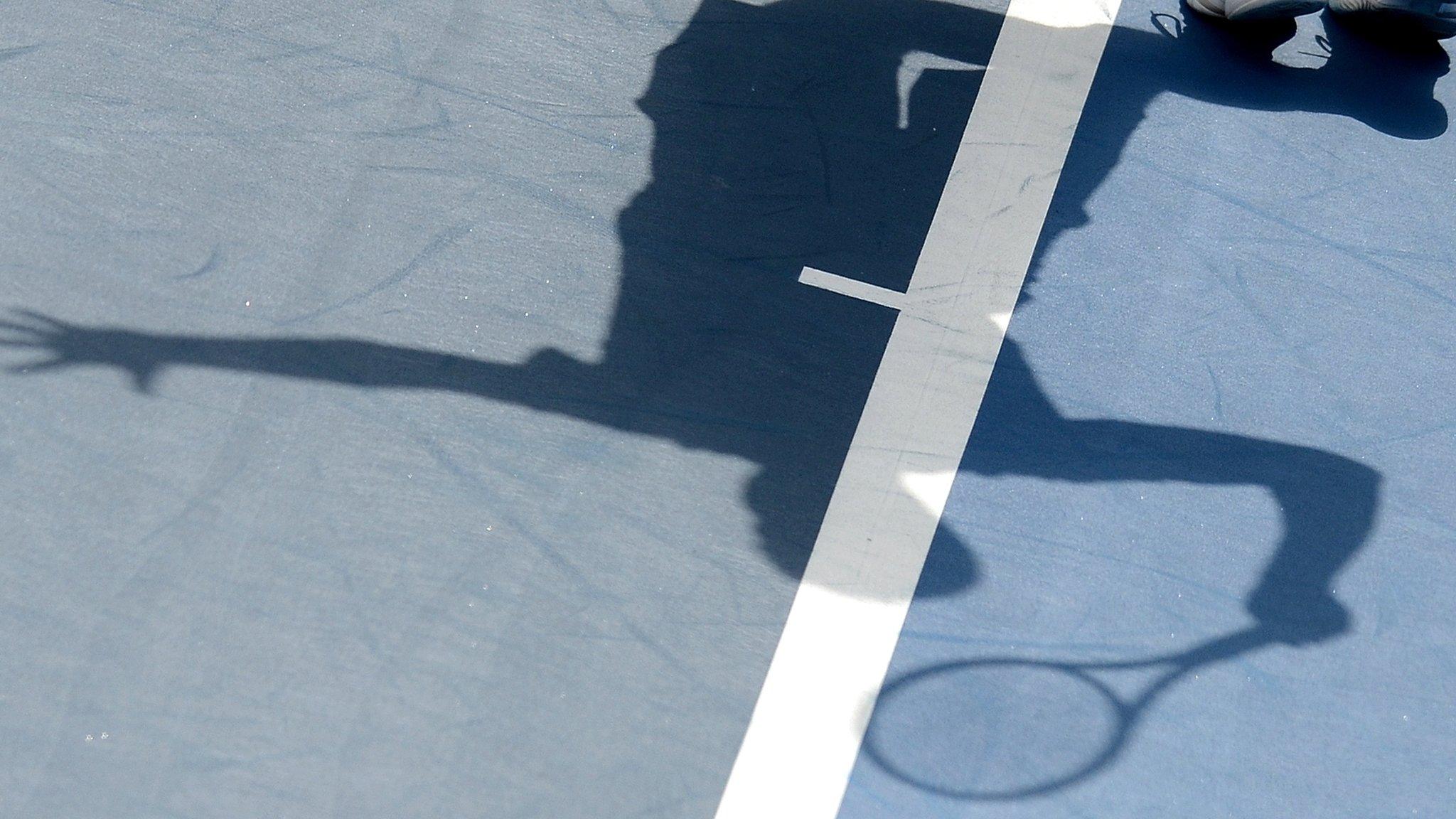 A tennis player casts a shadow