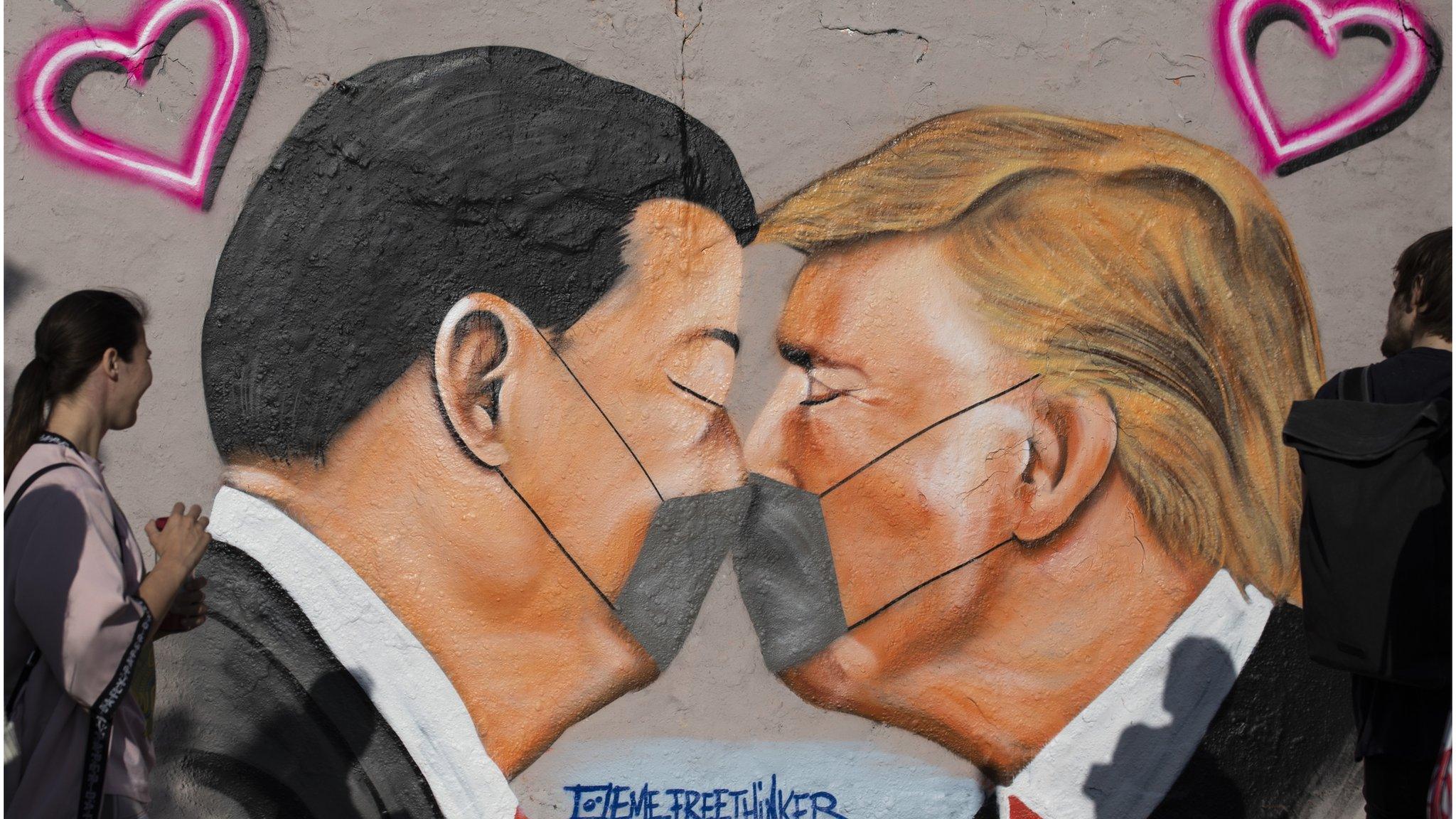 Street art shows US President Donald Trump and Chinese President Xi Jinping wearing protective mask and kissing at a section of the former Berlin Wall.