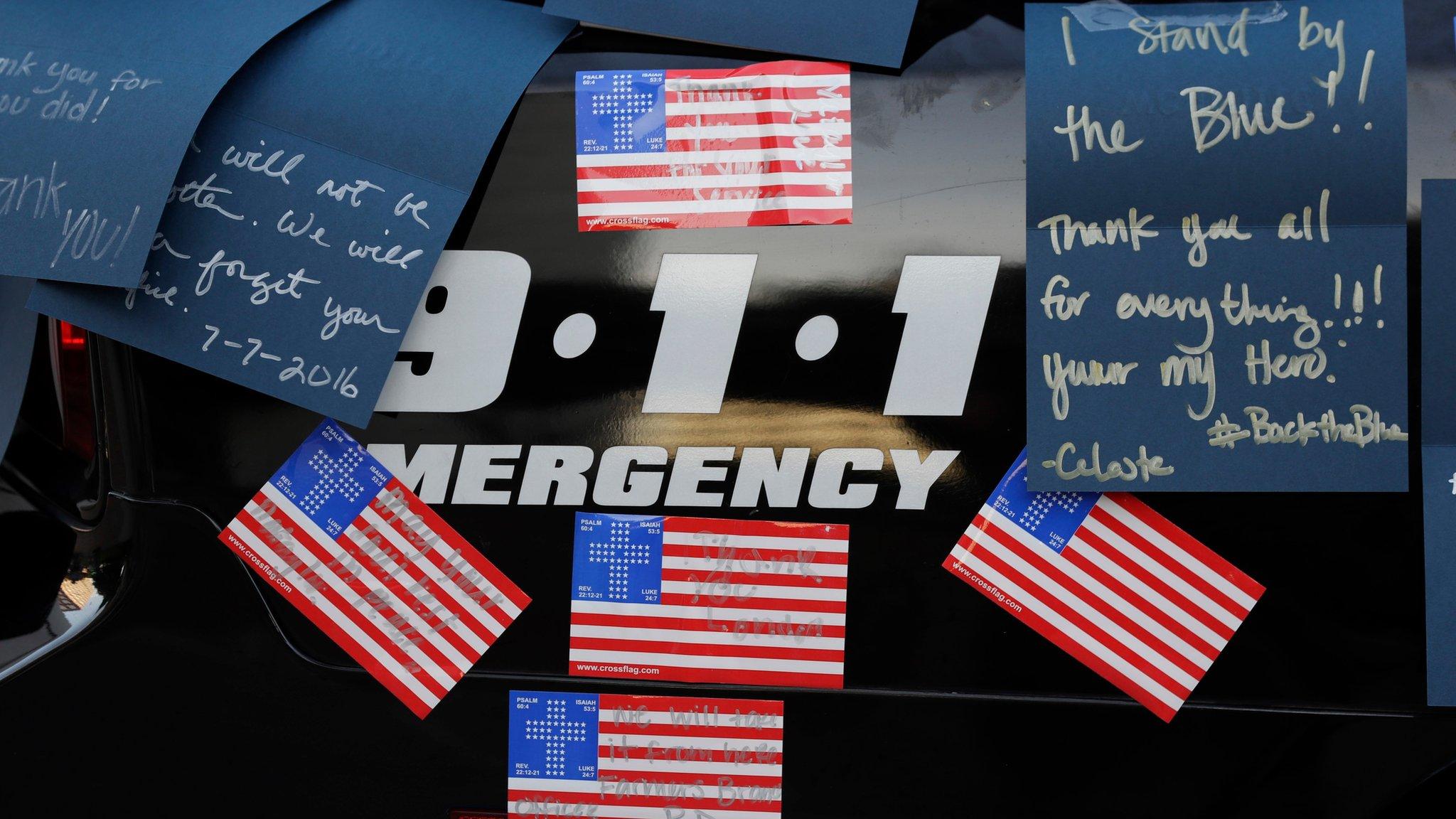 Notes are pinned to a police car at a make-shift memorial in front of the Dallas police department