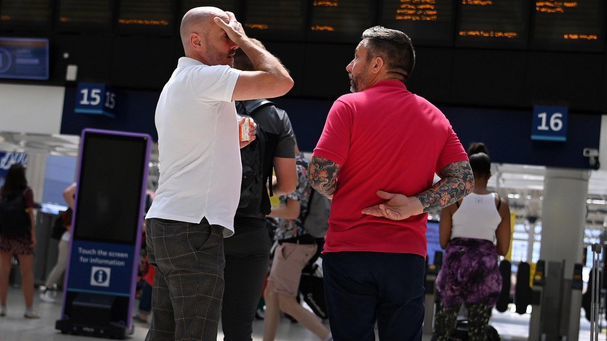 Commuters standing in front of rail boards at a station