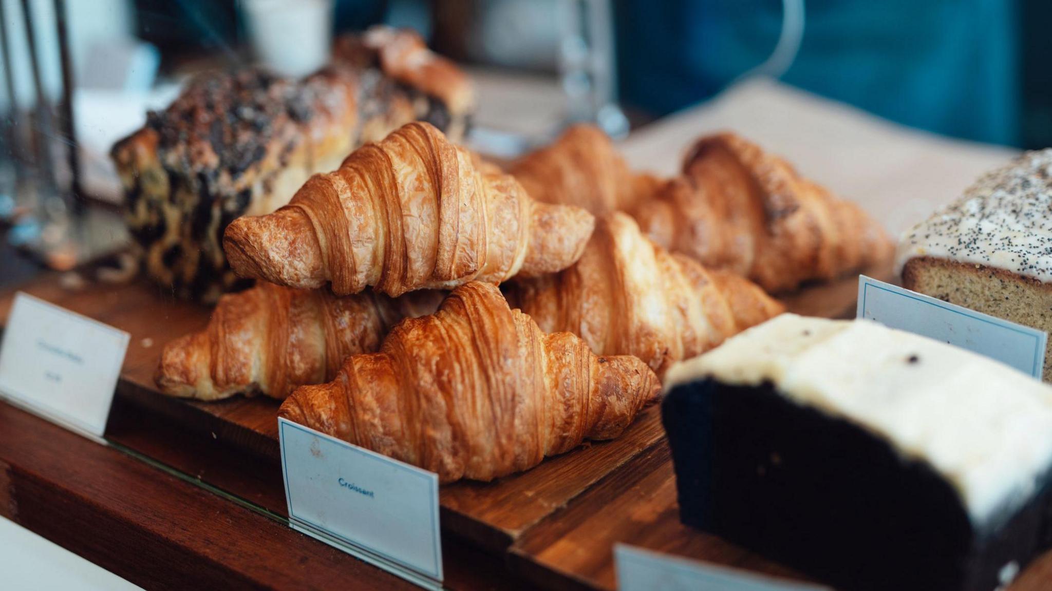 Croissants and cakes lined up in a bakery window