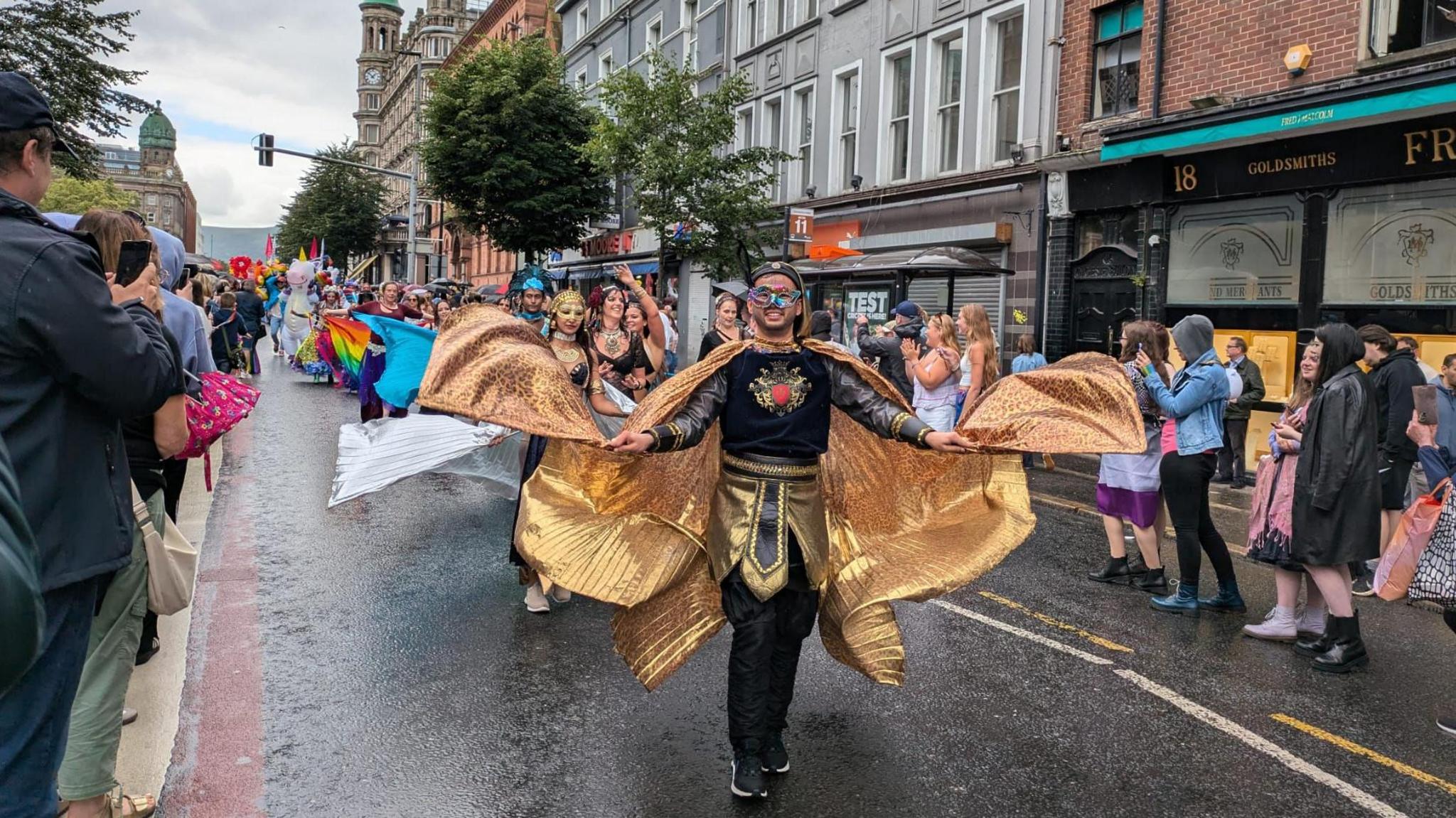 Person in a black and golden costume walking the the parade. 