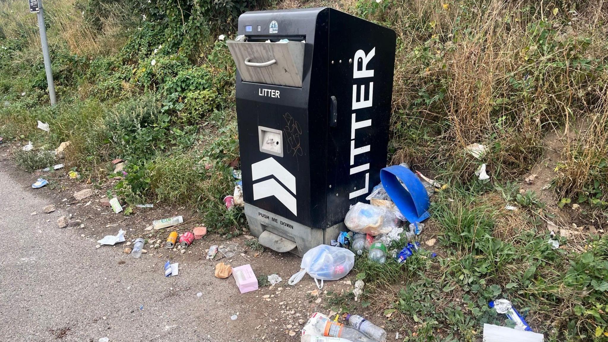 Rubbish overflowing in a black bin.