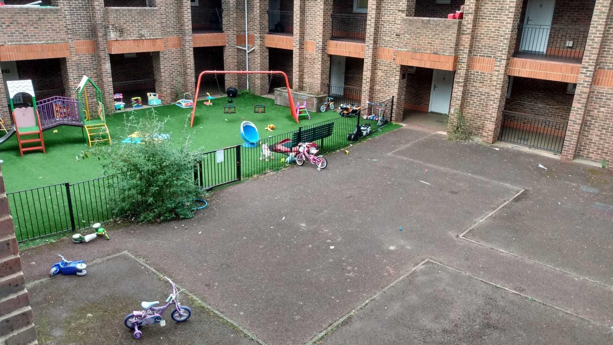 An aerial view of a children's play area and concrete section in the courtyard of the block of flats.