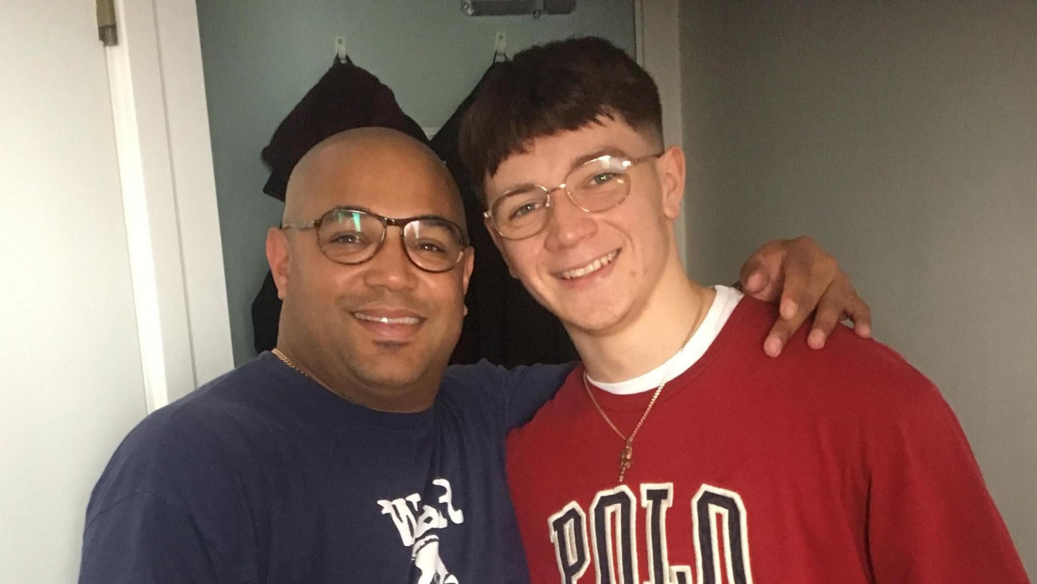 Lee and Rilee nurse standing together. le  has his arm round his son.