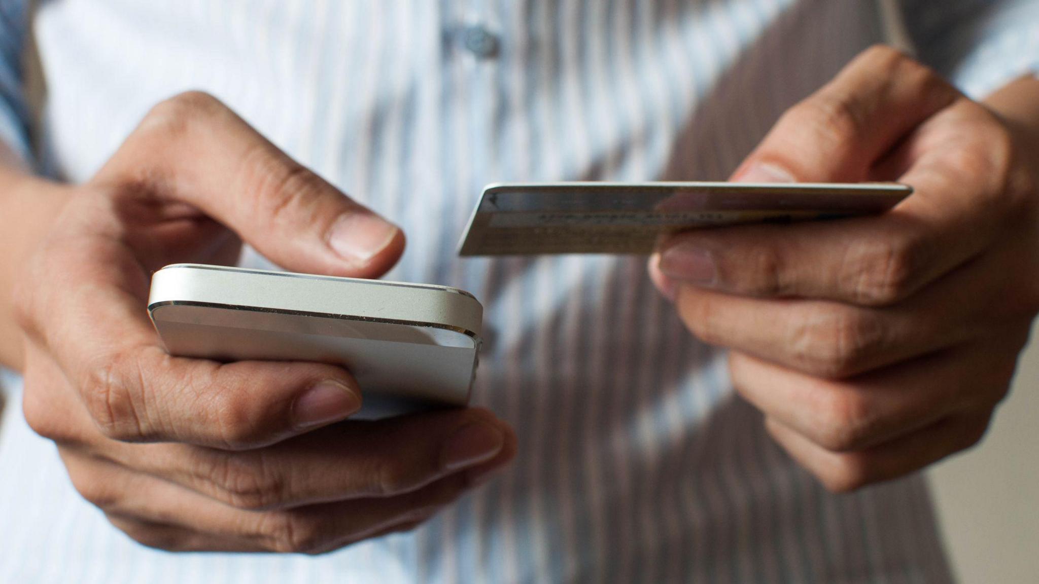 A stock image of a man buying online using his mobile phone and credit card