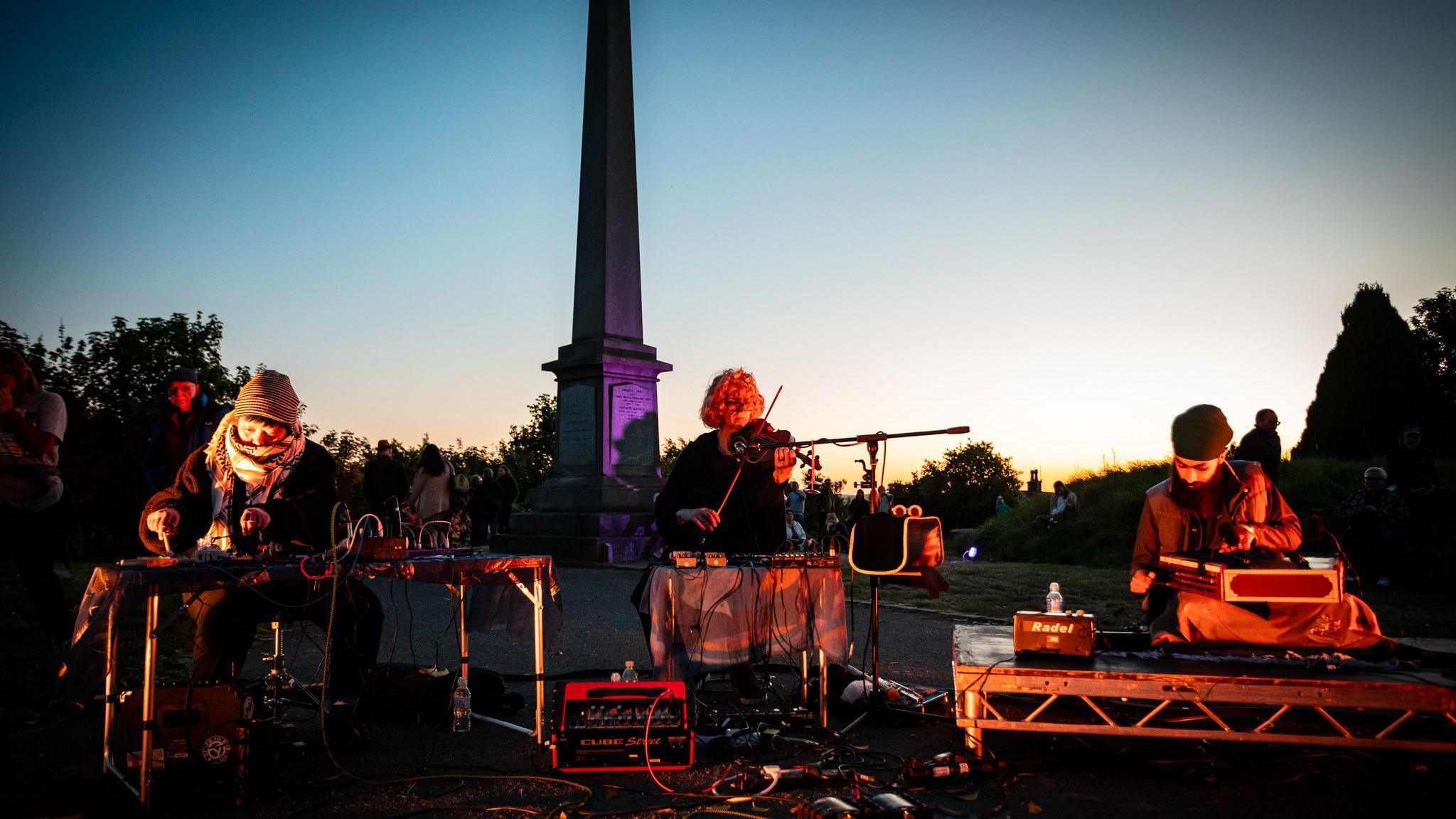 People playing instruments while the sun is going down