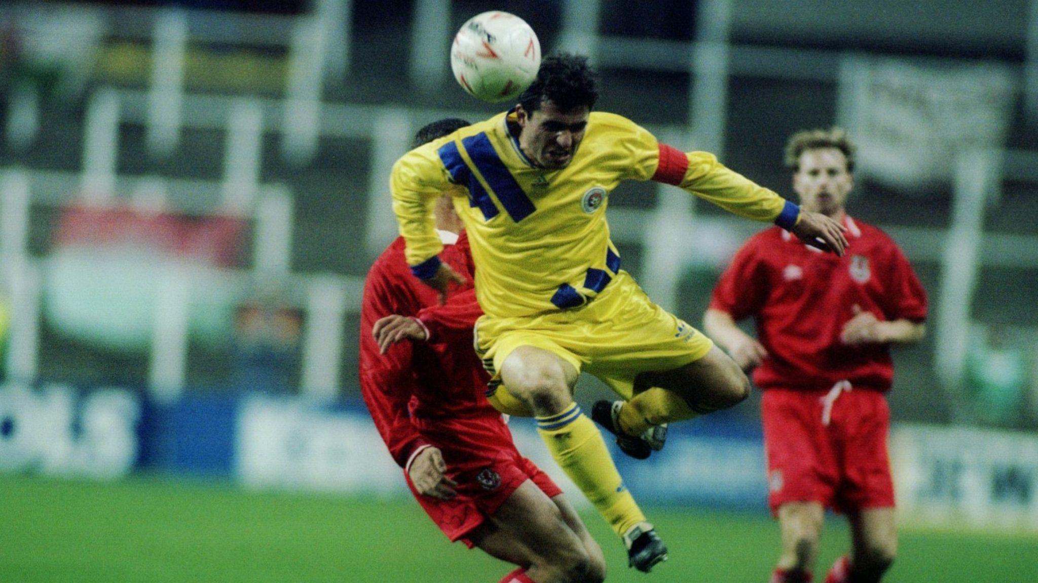 Gheorghe Hagi heads the ball as Paul Bodin looks on