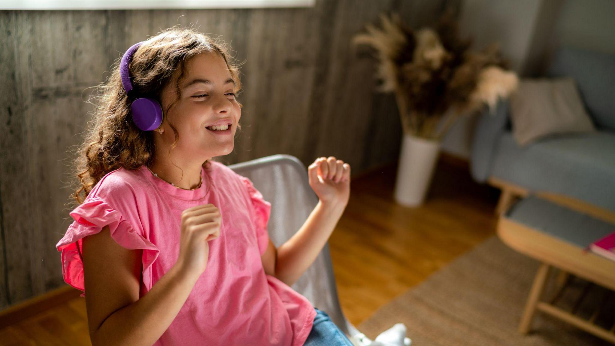 child listening to music with headphones on, looking happy