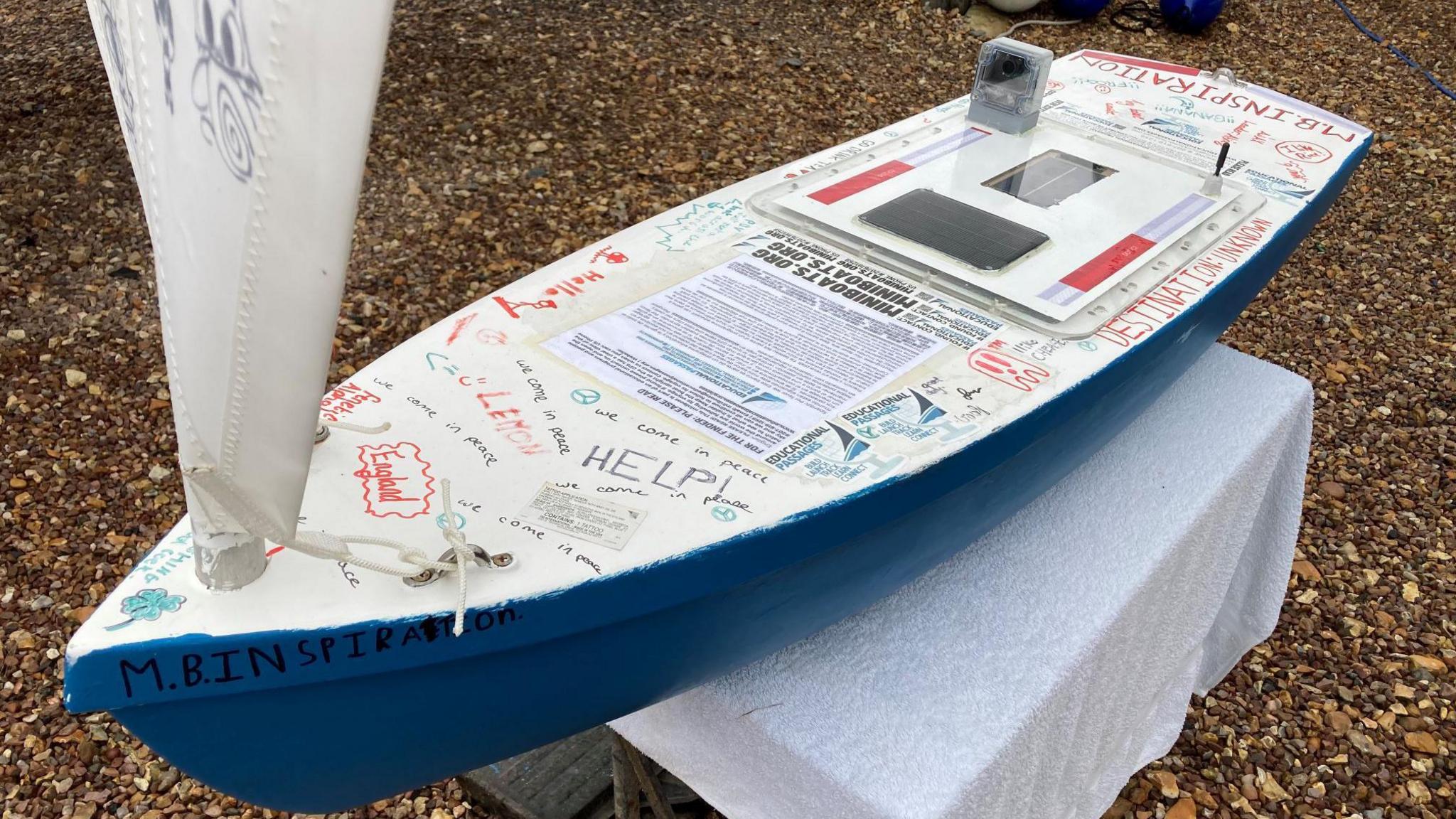 The refurbished boat displayed on a stand with messages written across the structure