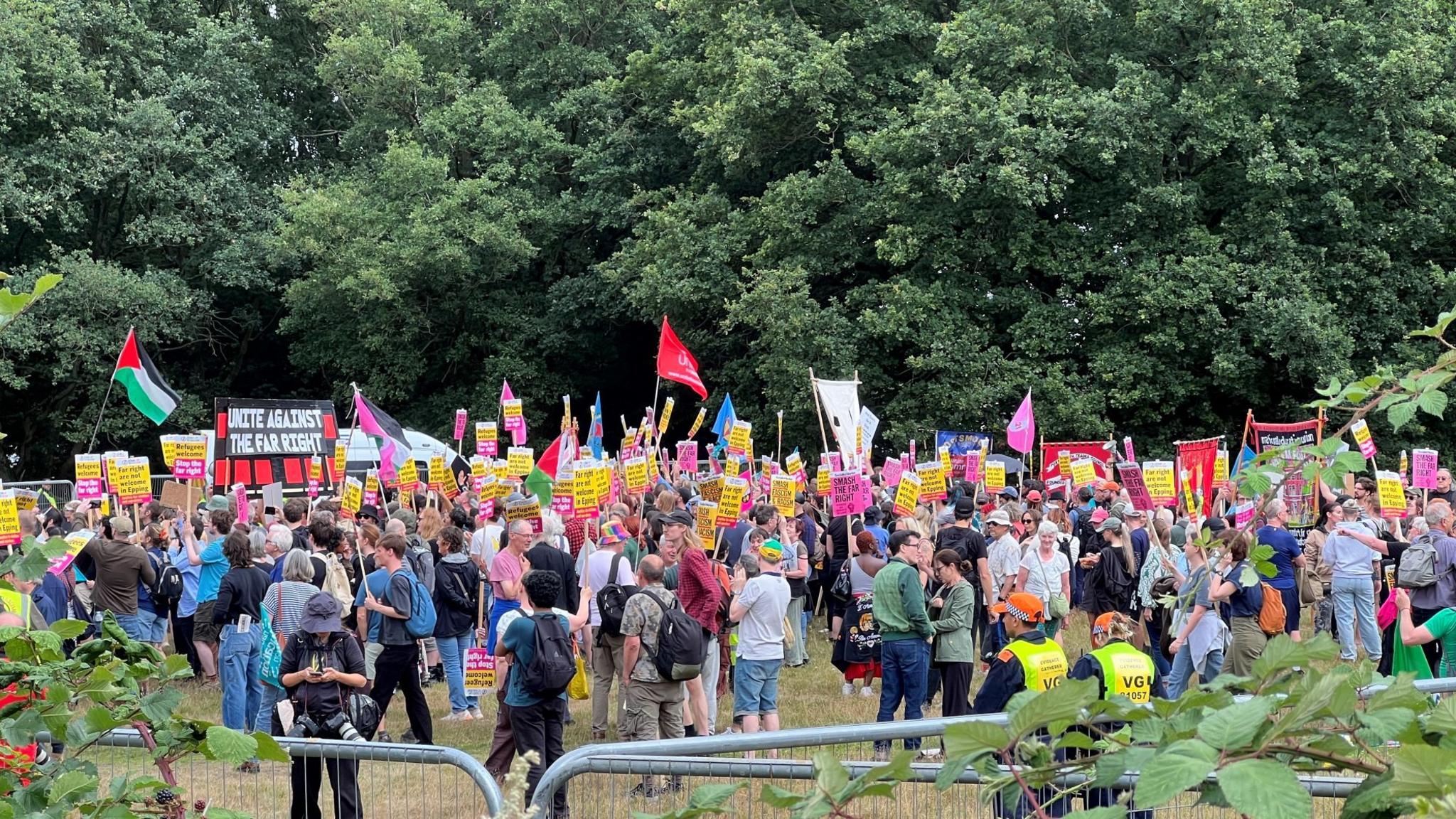A large group of people holding banners and flags, including the Palestinian flag.