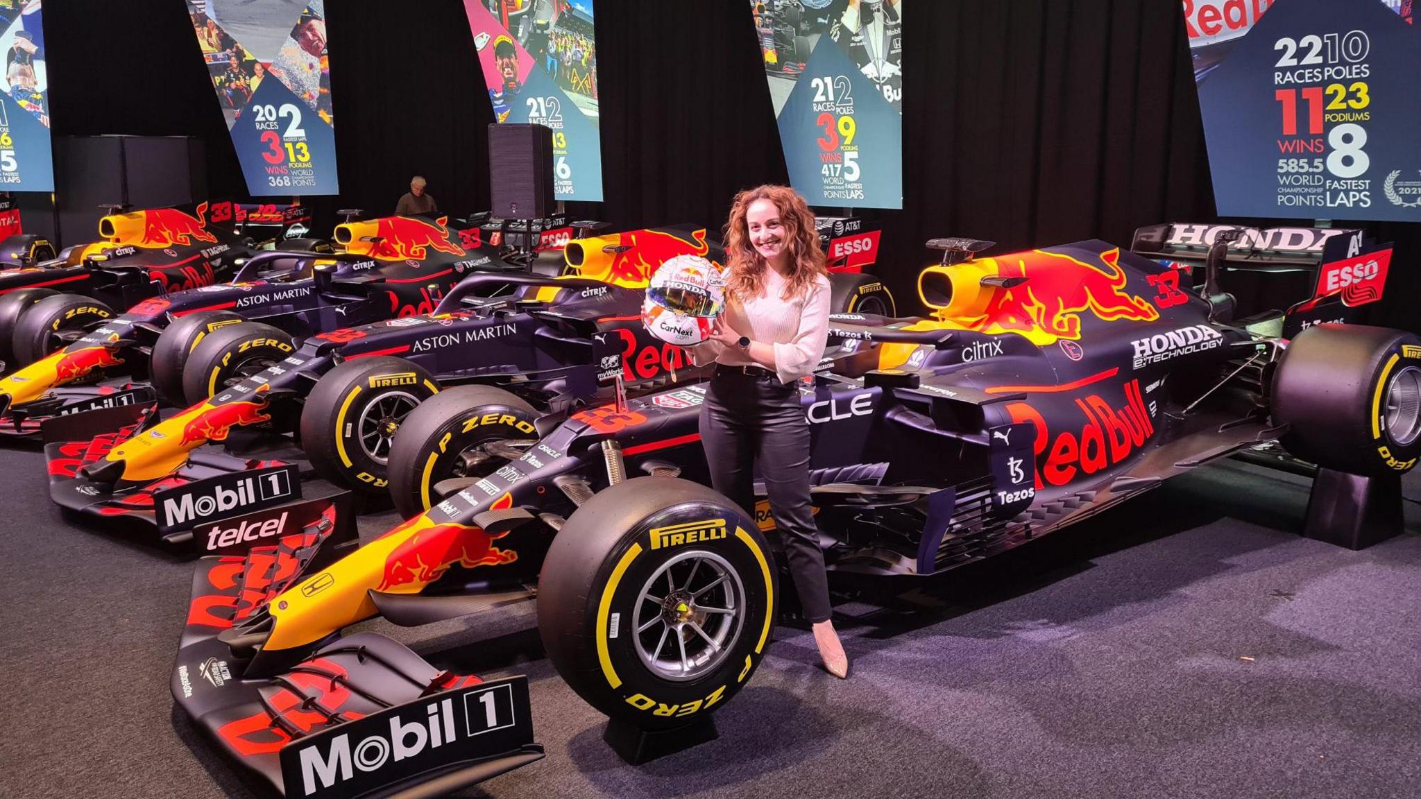 Andra Patricia holds a helmet next to a car