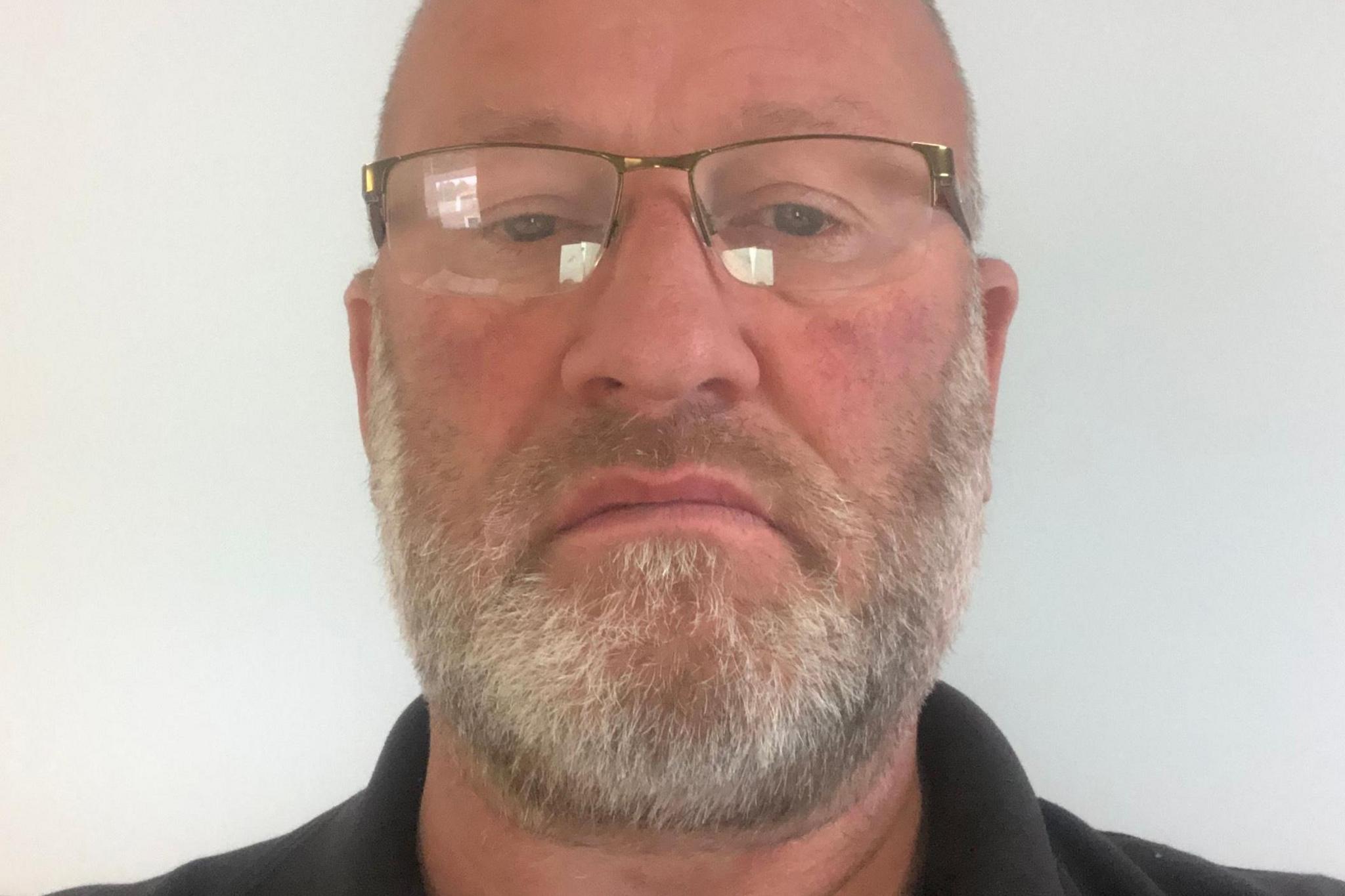 A bearded Neil Hallsworth wearing glasses looking straight ahead