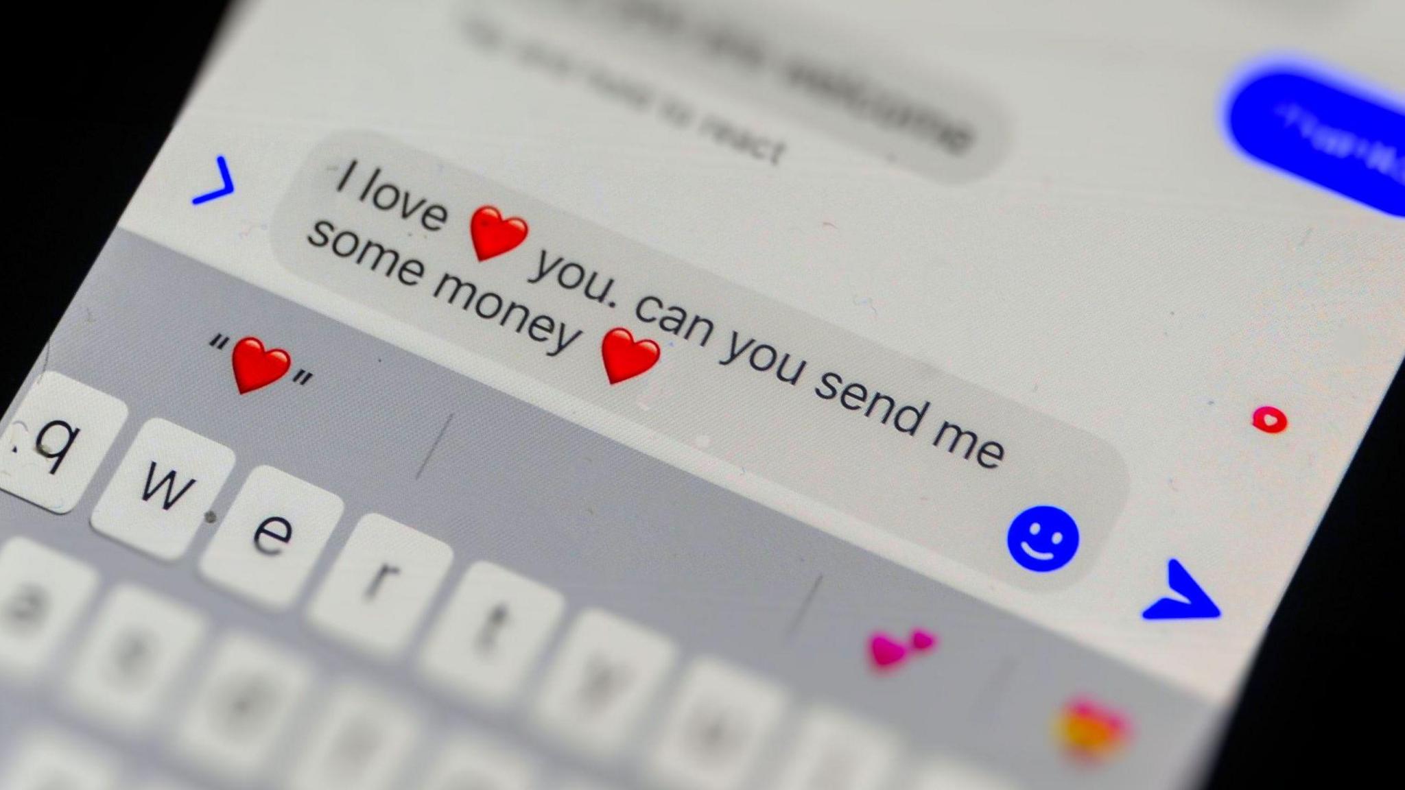 A mobile phone screen open to a messaging app with a incoming message on it which reads: "I love you. Can you send me some money." There are heart emojis on the message.