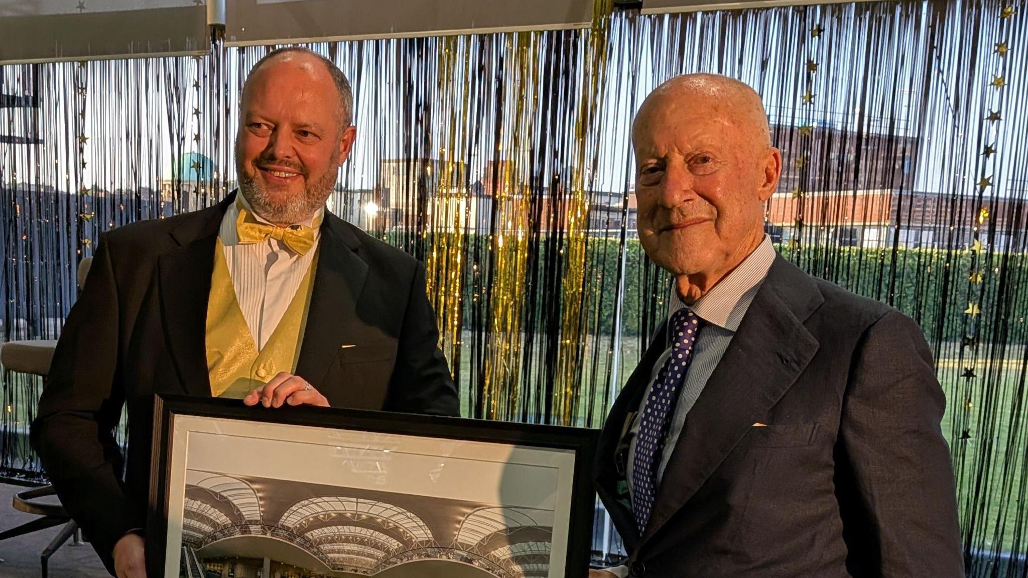 Lord Foster smiles at the camera as he is presented with a photo of the interior of the building's entrance.