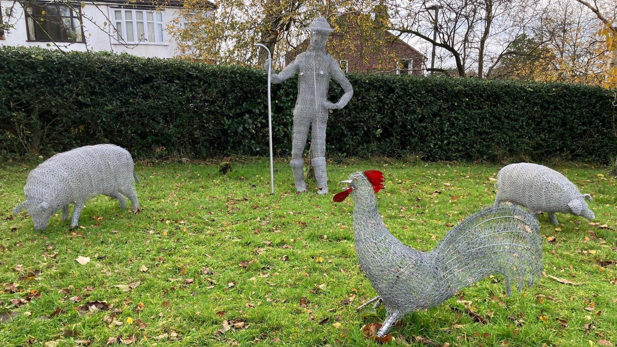 A sheep, shepherd, cockerel and pig on display in the orchard at Werneth Low country park.