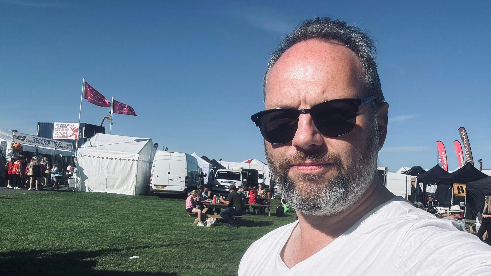 Sion Lewis wearing sun glasses and a t shirt on a campground on a sunny summer day