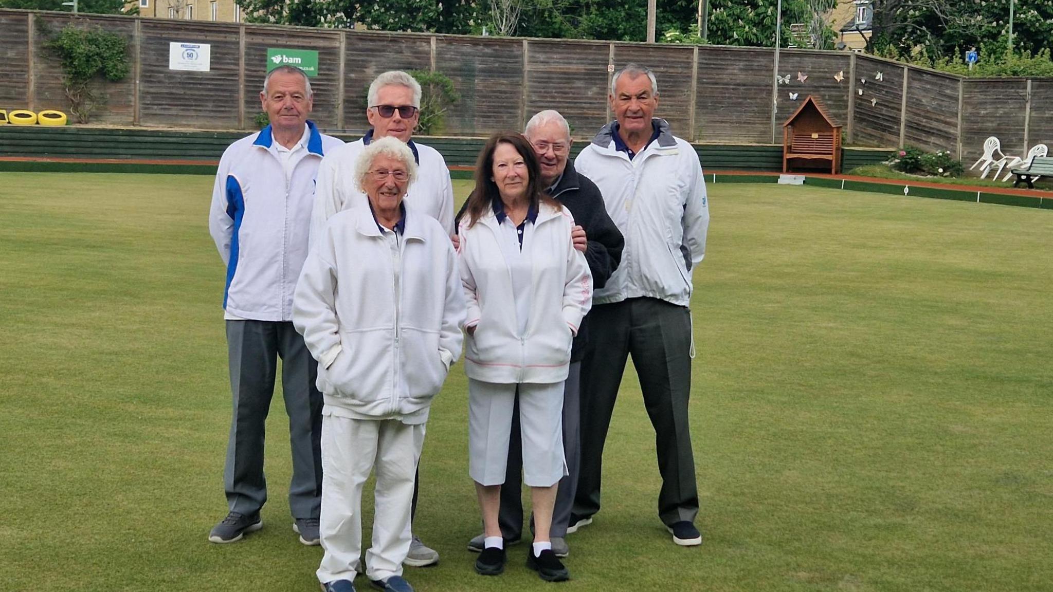 Members of Halls Bowls Club pose wearing whites on their green.