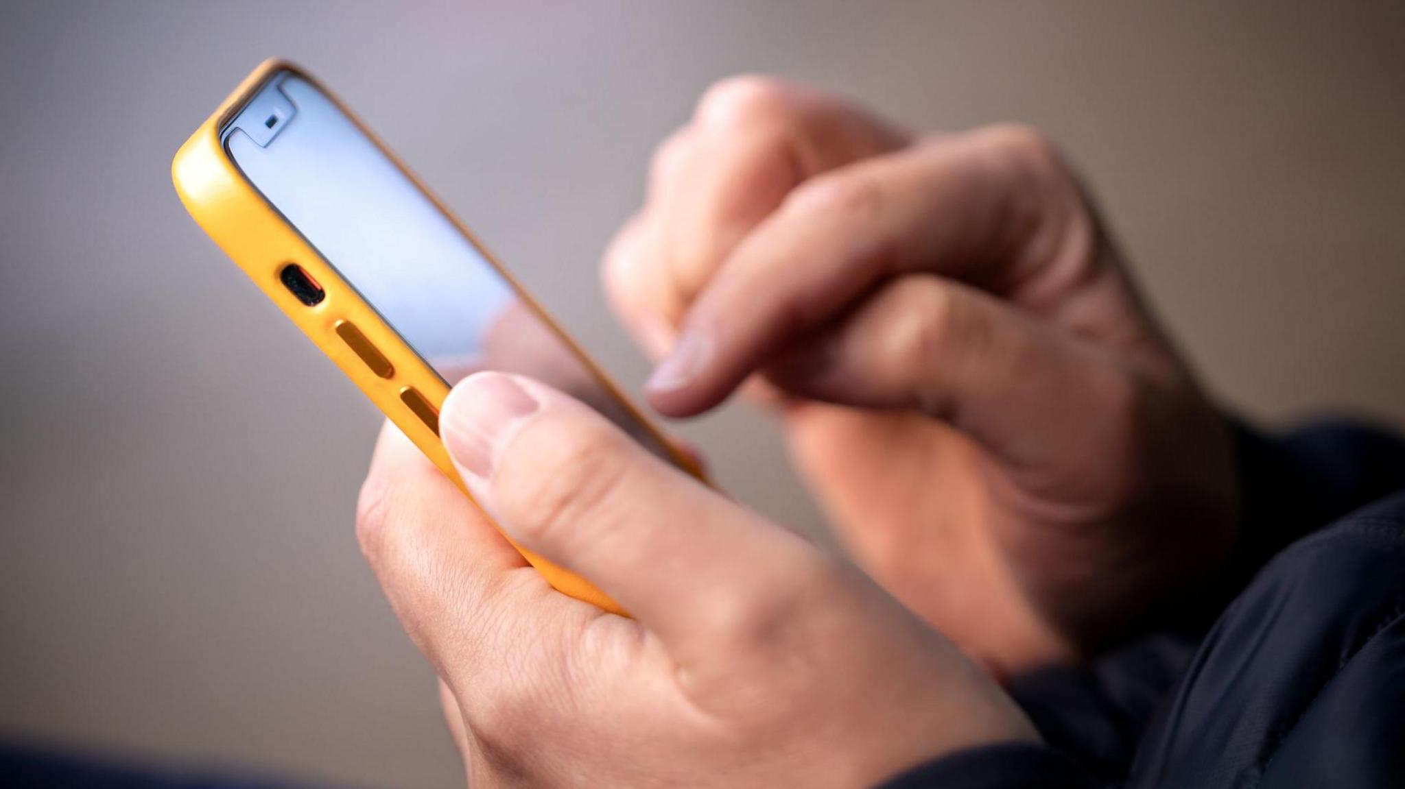 A close-up picture of a man using a smartphone. 