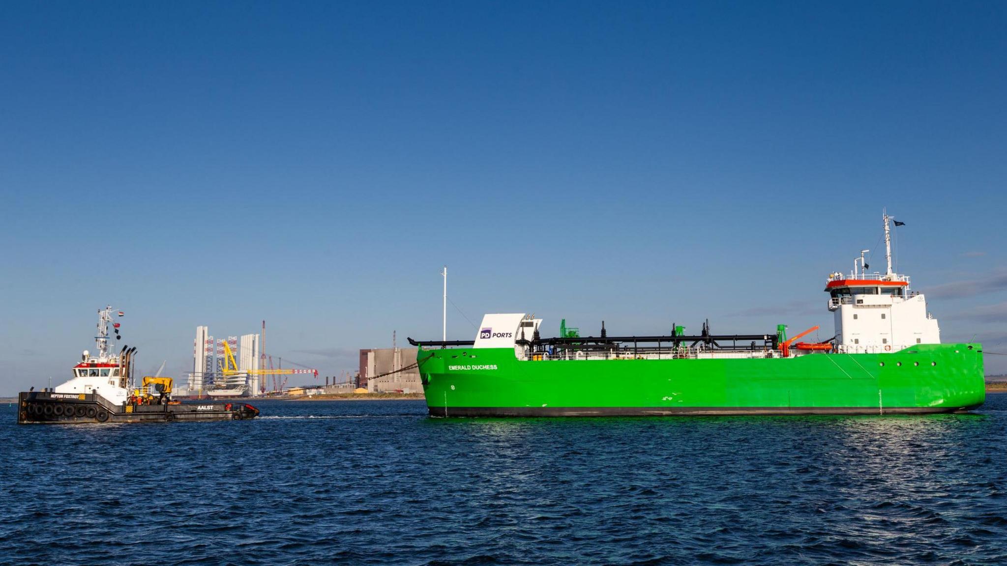 The Emerald Duchess being pulled by a tug on the Tees. The port is in the background.