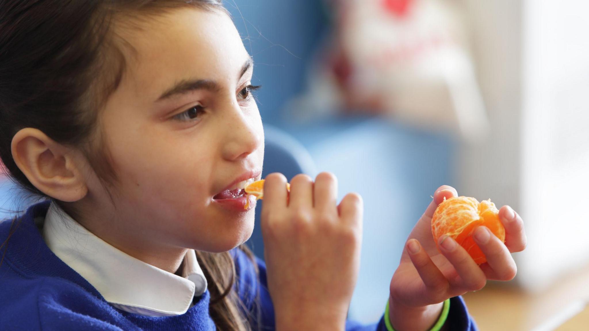 A girl eating a tangerine. 