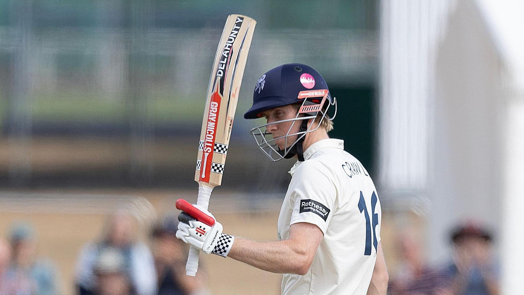 Zak Crawley has his eyes shut but his bat raised upon passing 50 for Kent