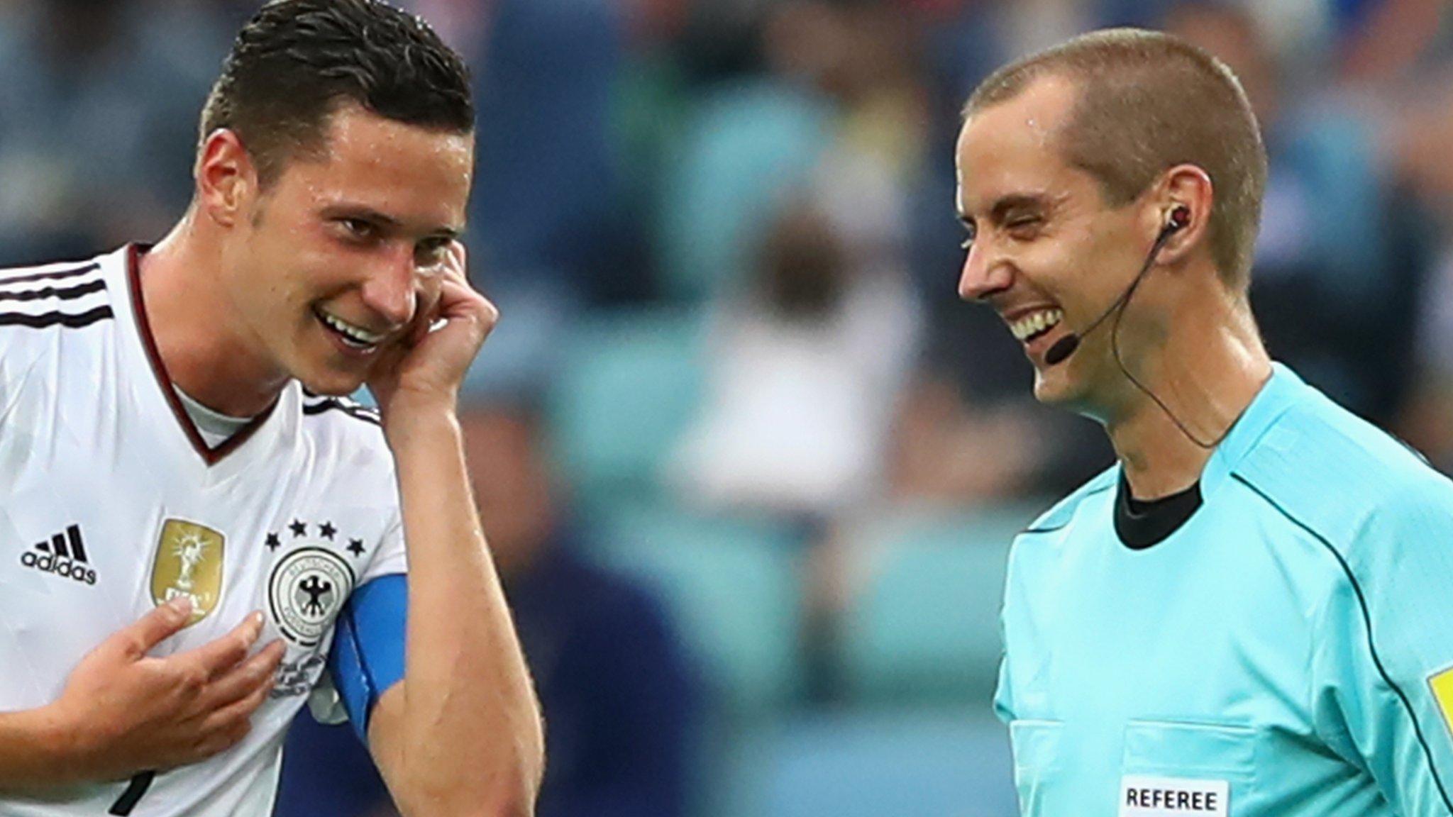 A referee jokes with Julian Draxler over the video referral communication system