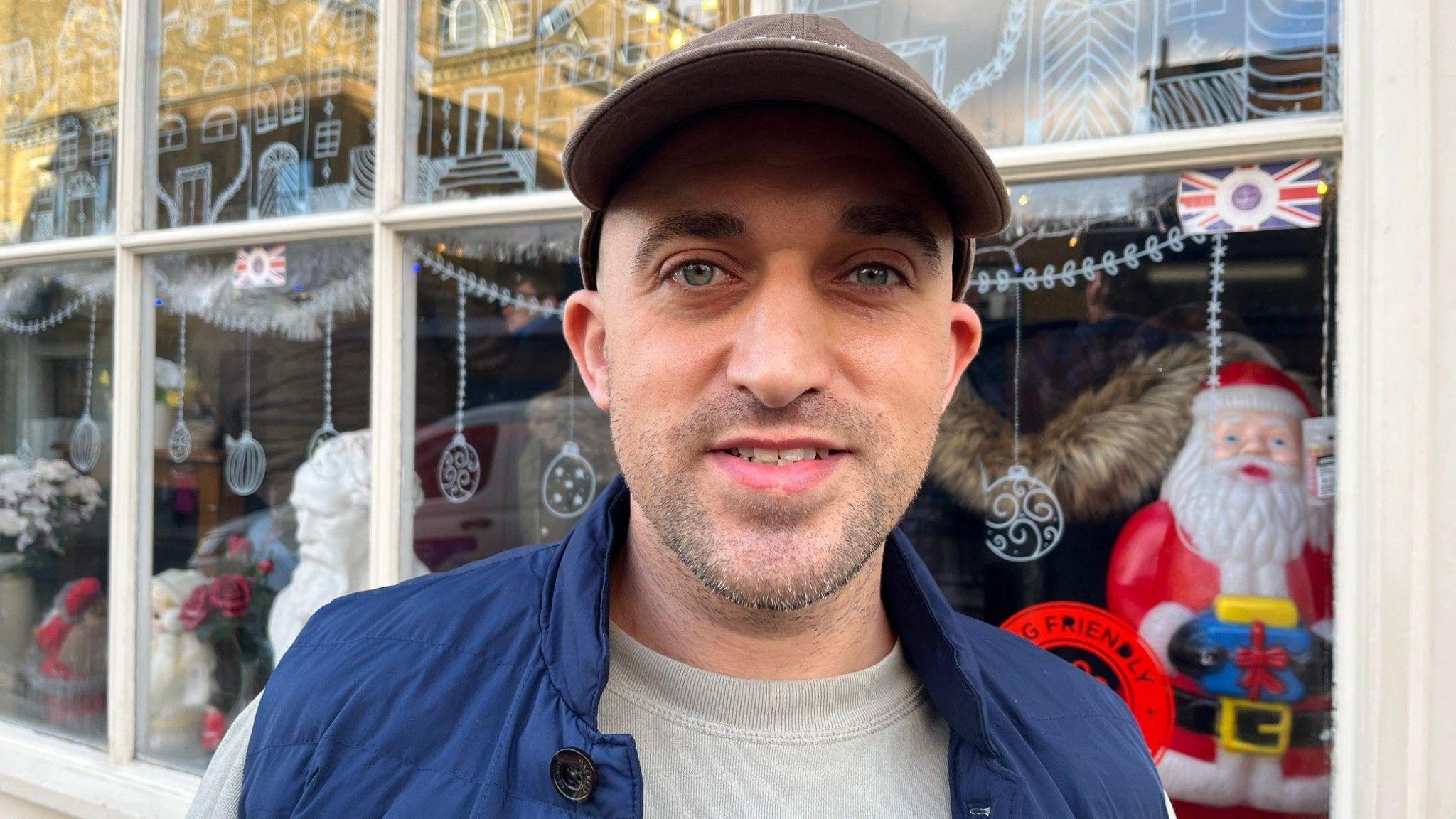 Steve Morgan stands outside his shop in a cap and blue gilet