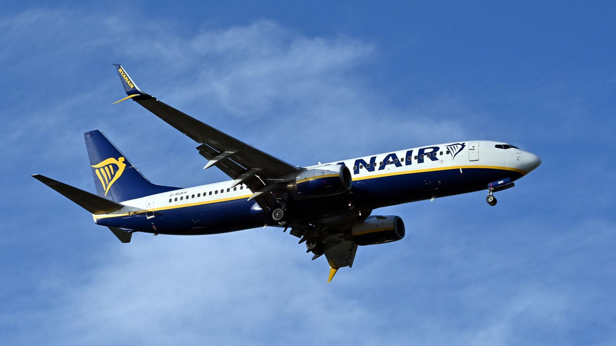 A Ryanair plane, seen here at Edinburgh Airport, flying against a background of a blue sky