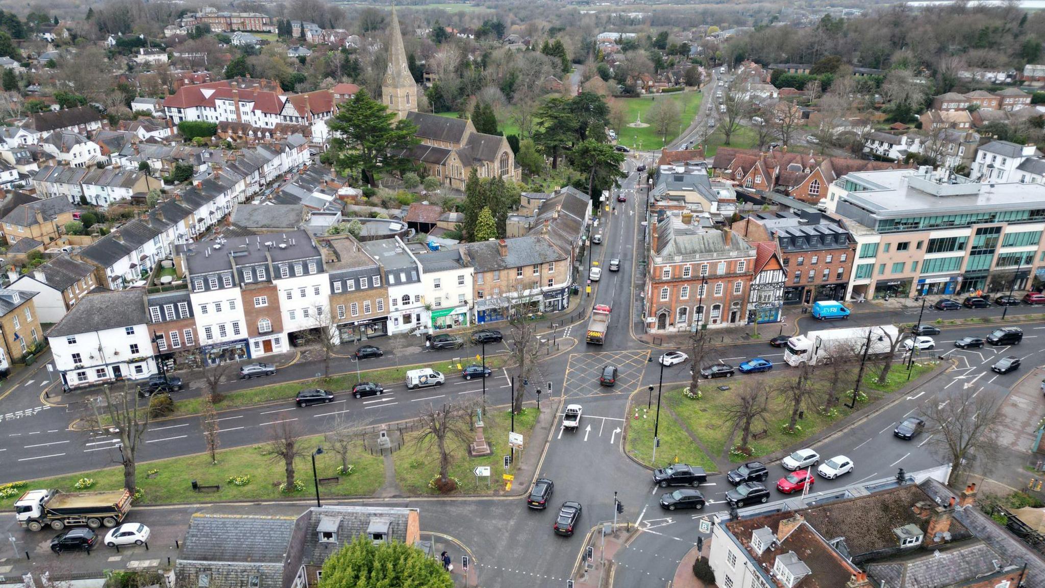 An aerial view of Esher which shows a crossroads and shops and houses along the sides of the streets