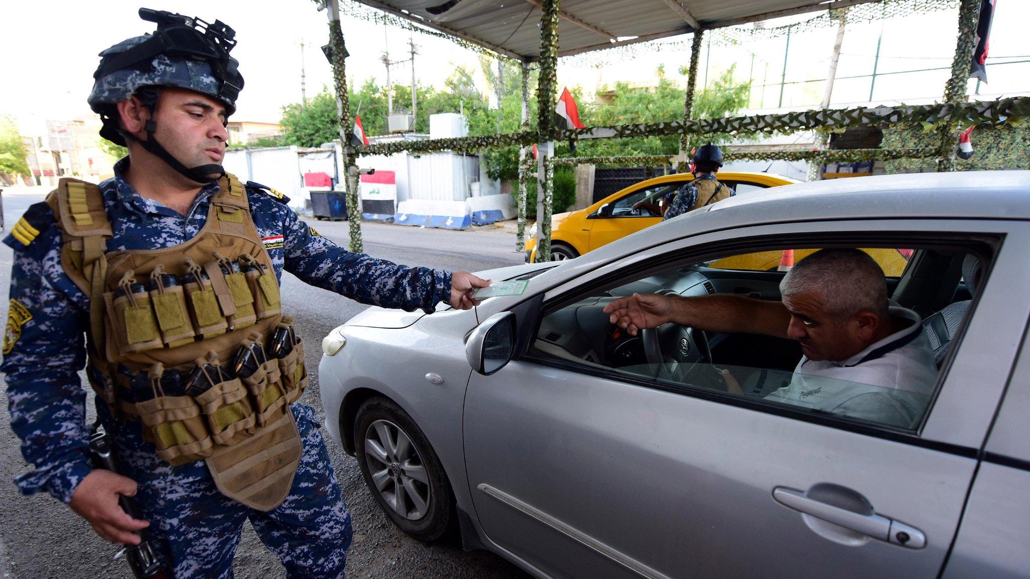 Iraqi police officer checks the identity papers of a driver in Baghdad's Karrada district (12 May 2019)