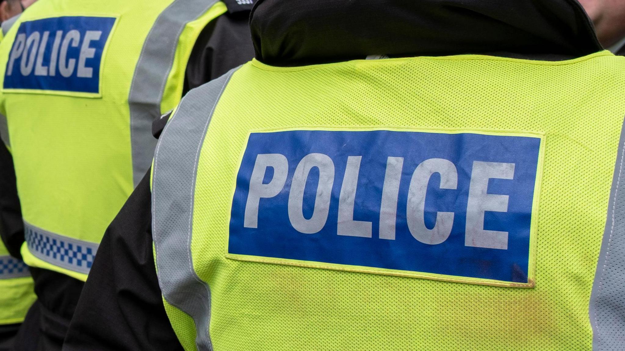 The back of two high-vis police vests