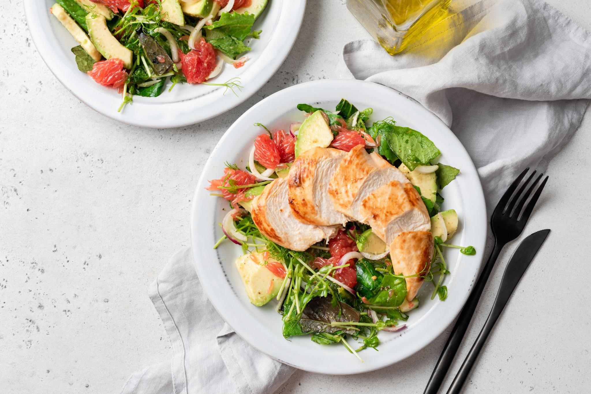 Grilled chicken salad with avocado on a white plate 
