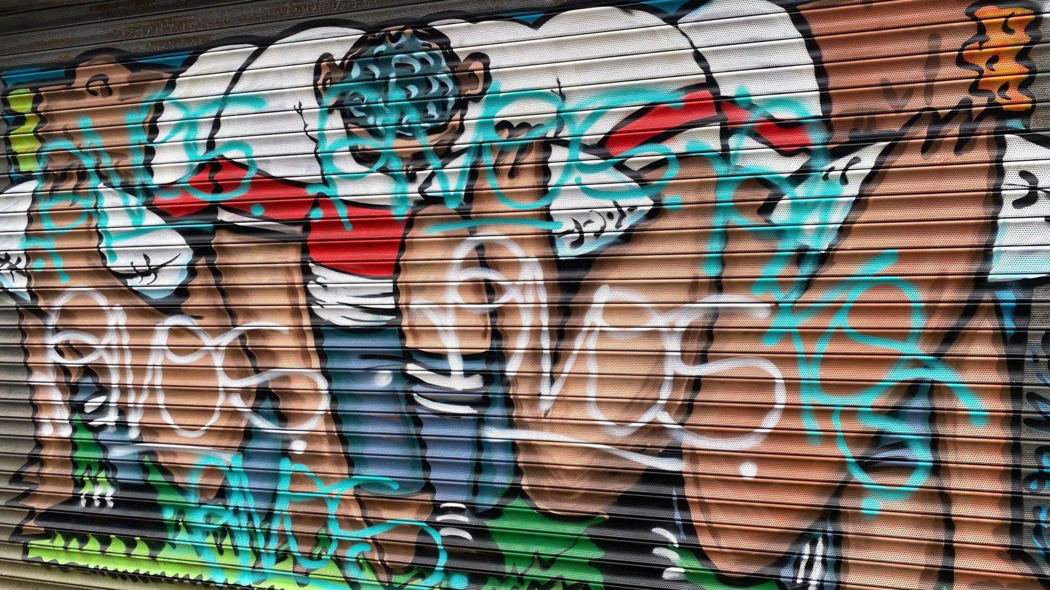 Mural of rugby players covered in graffiti tags 