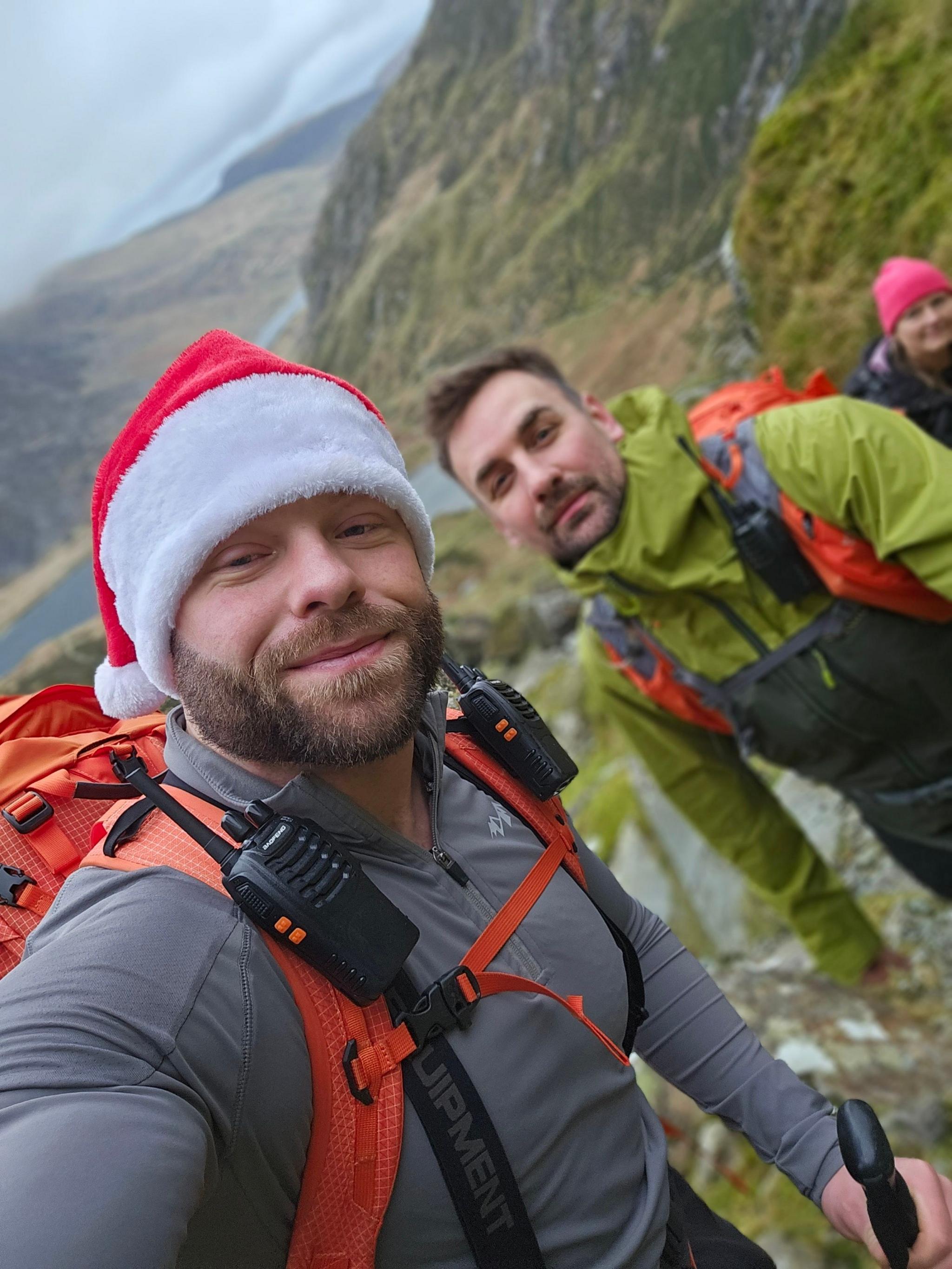 Mr Jones (left) pictured, has a thick mousy brown beard and is wearing a christmas hat. Mr Churchward (right) wears a green rainmac, orange backpack, has dark hair and stubble. 