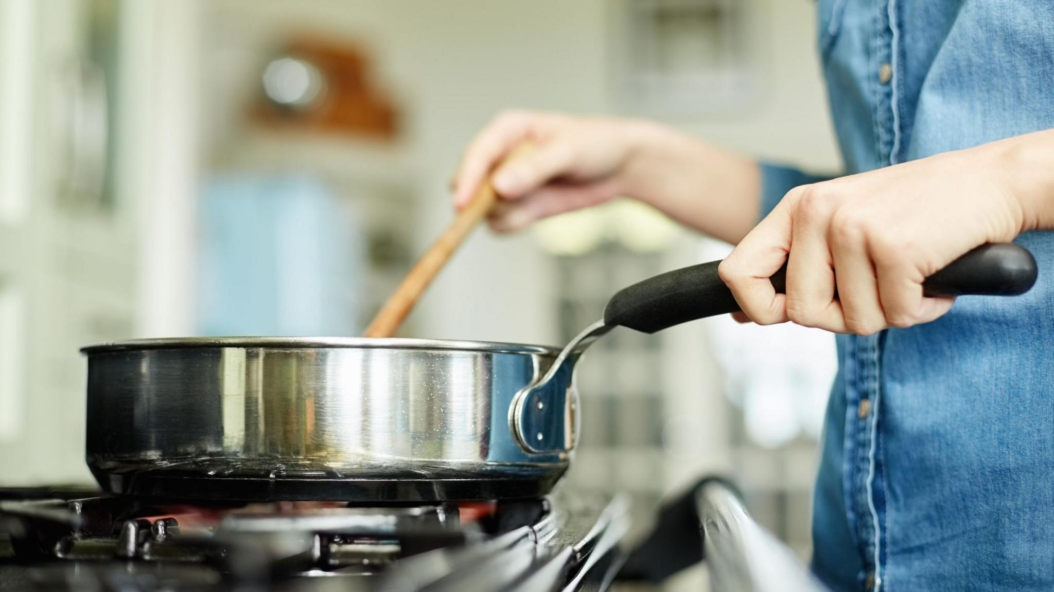 Women cooking with a frying pan over a gas hob