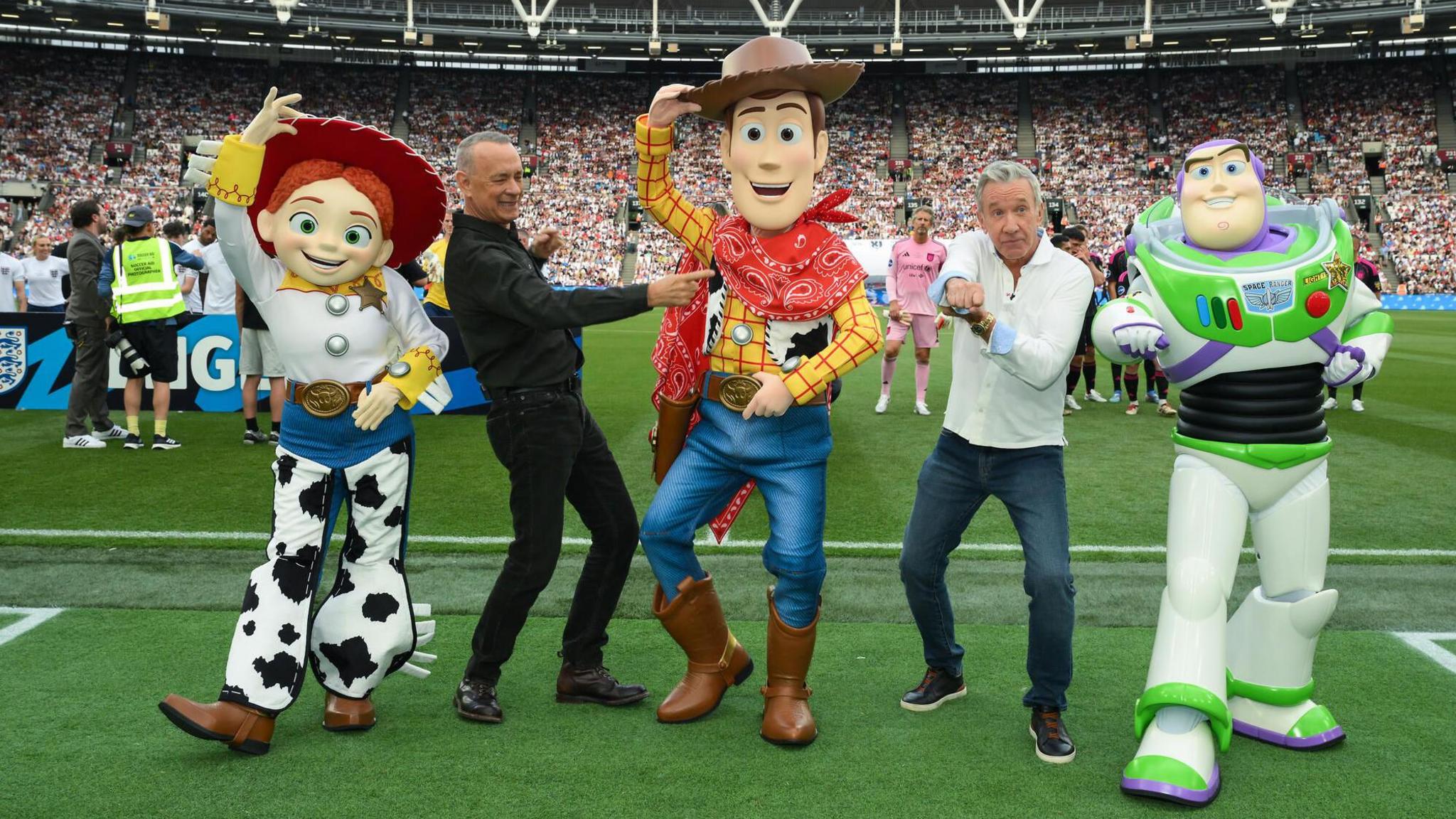 Tom Hanks and Tim Allen on the pitch, along with Woody, Buzz Lightyear and Jessie. 