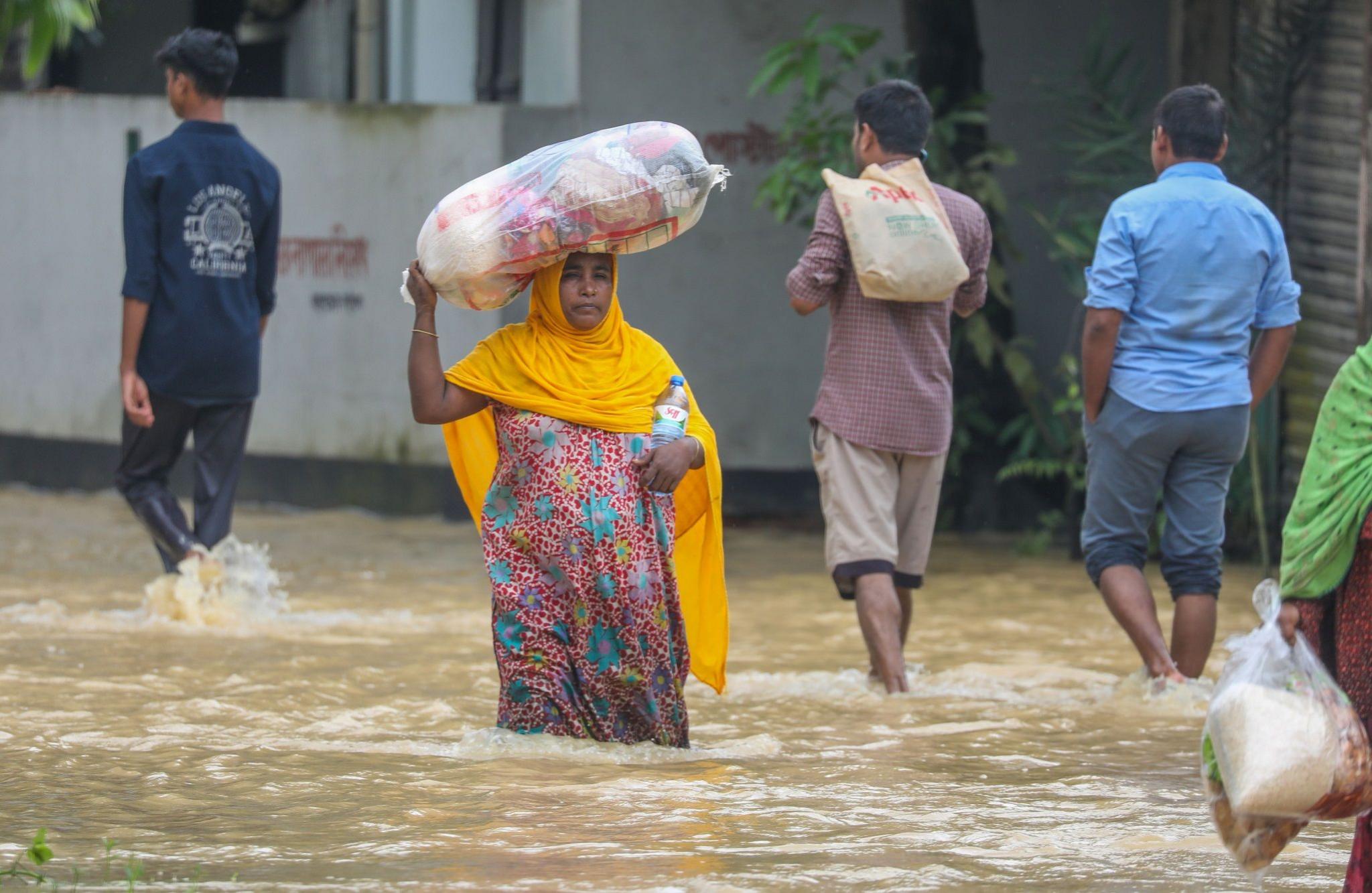 People wade through floodwater at a flood-affected area in Burichong, Comilla district, Bangladesh