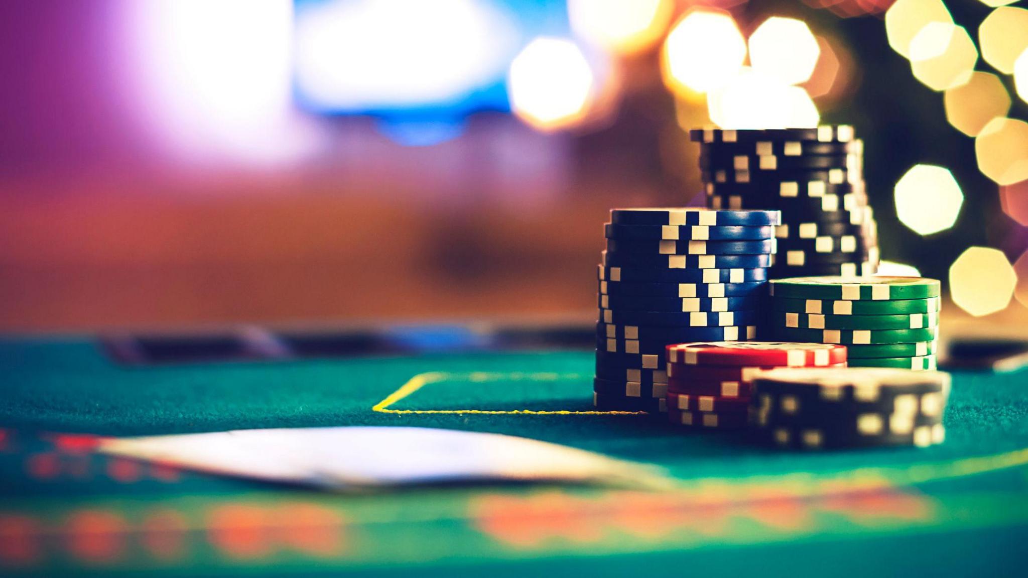 A poker table with a stack of chips. Bokeh lights in the background. 